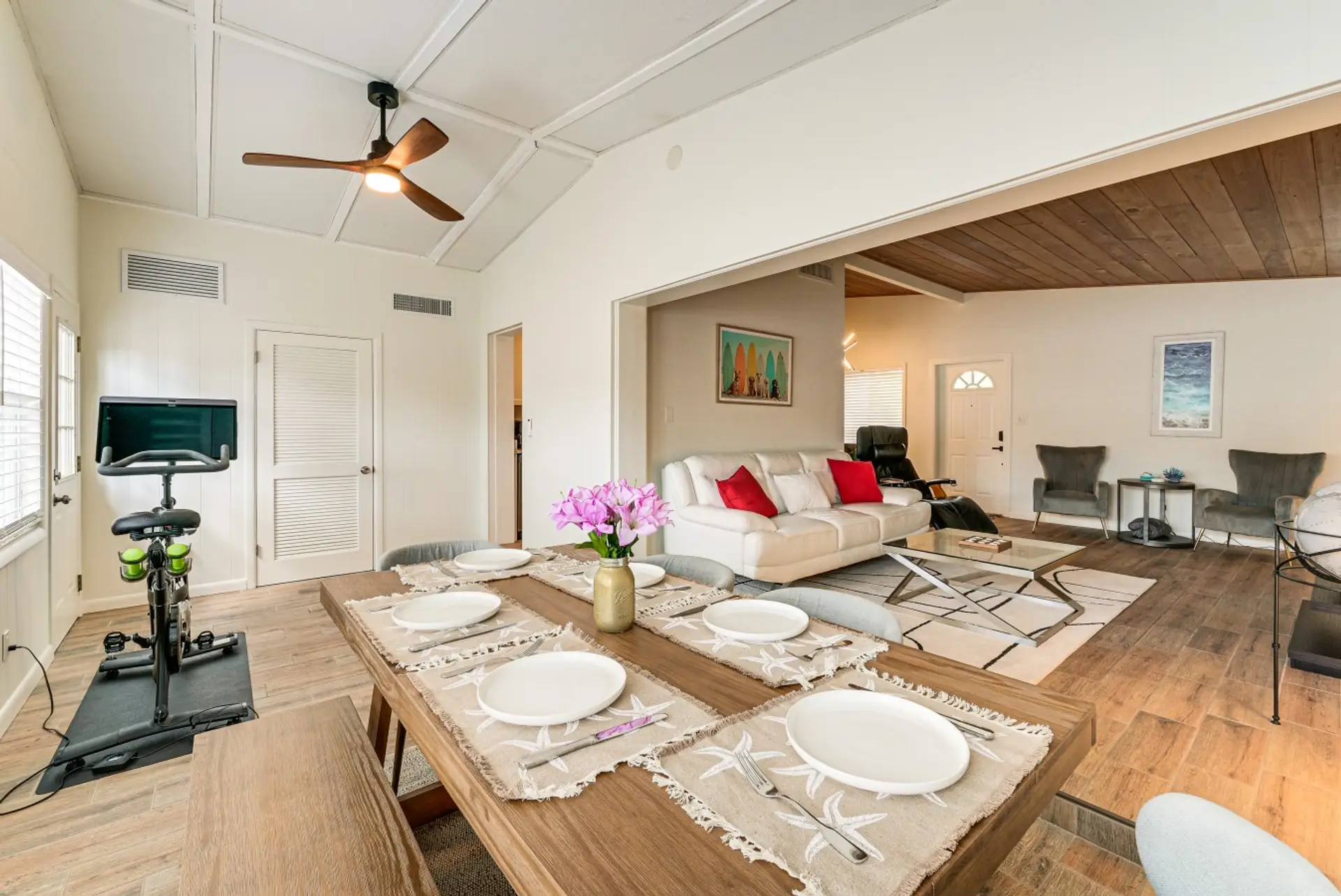 Indoor dining room for 6, ceiling fan, a Pelaton bike, Smart TV and several sitting areas.