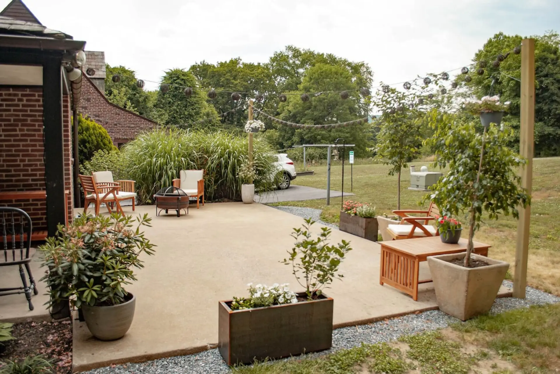 Outdoor patio with seating, plants, and string lights in a garden setting