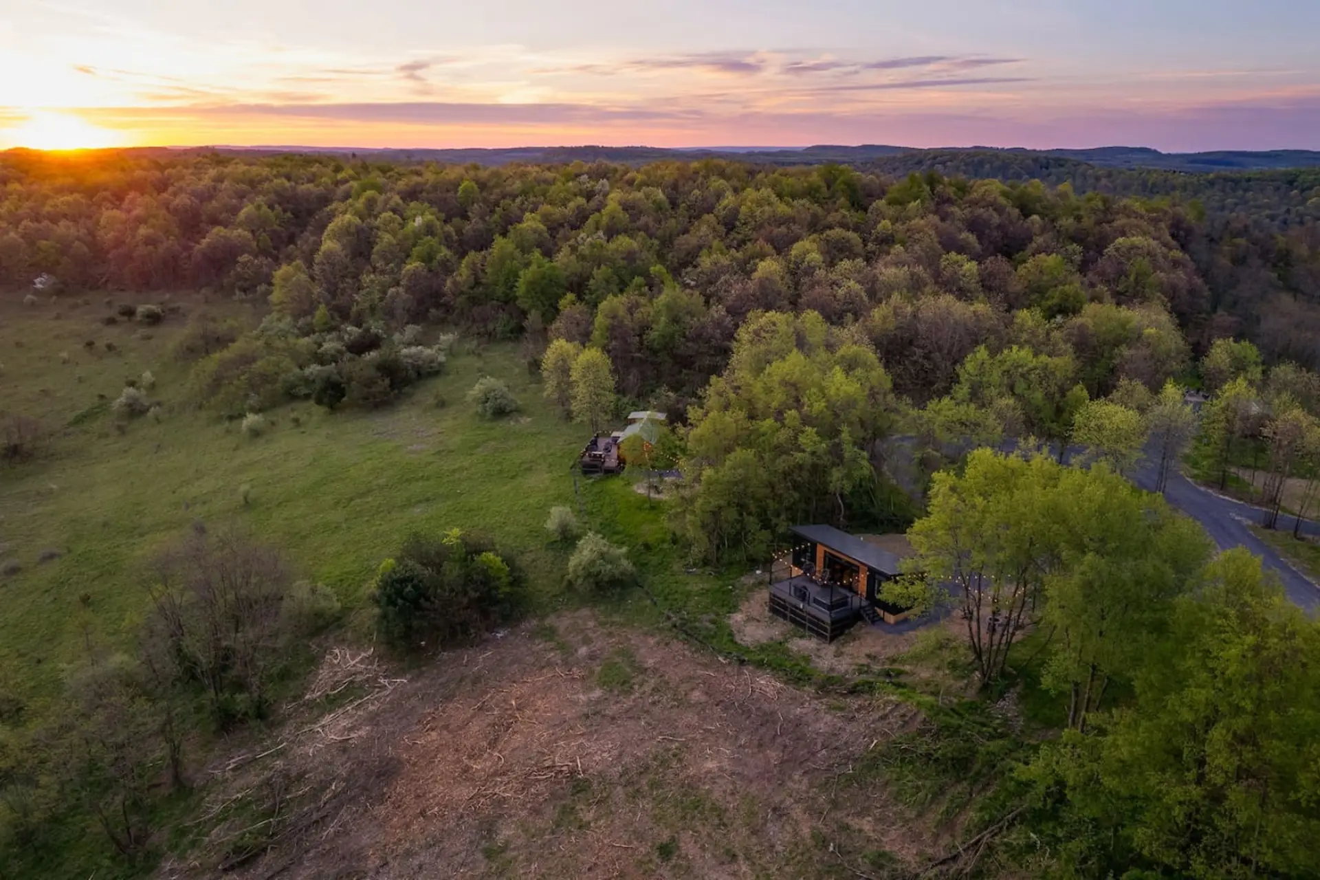 Expansive aerial view of the cabin and dense forest
