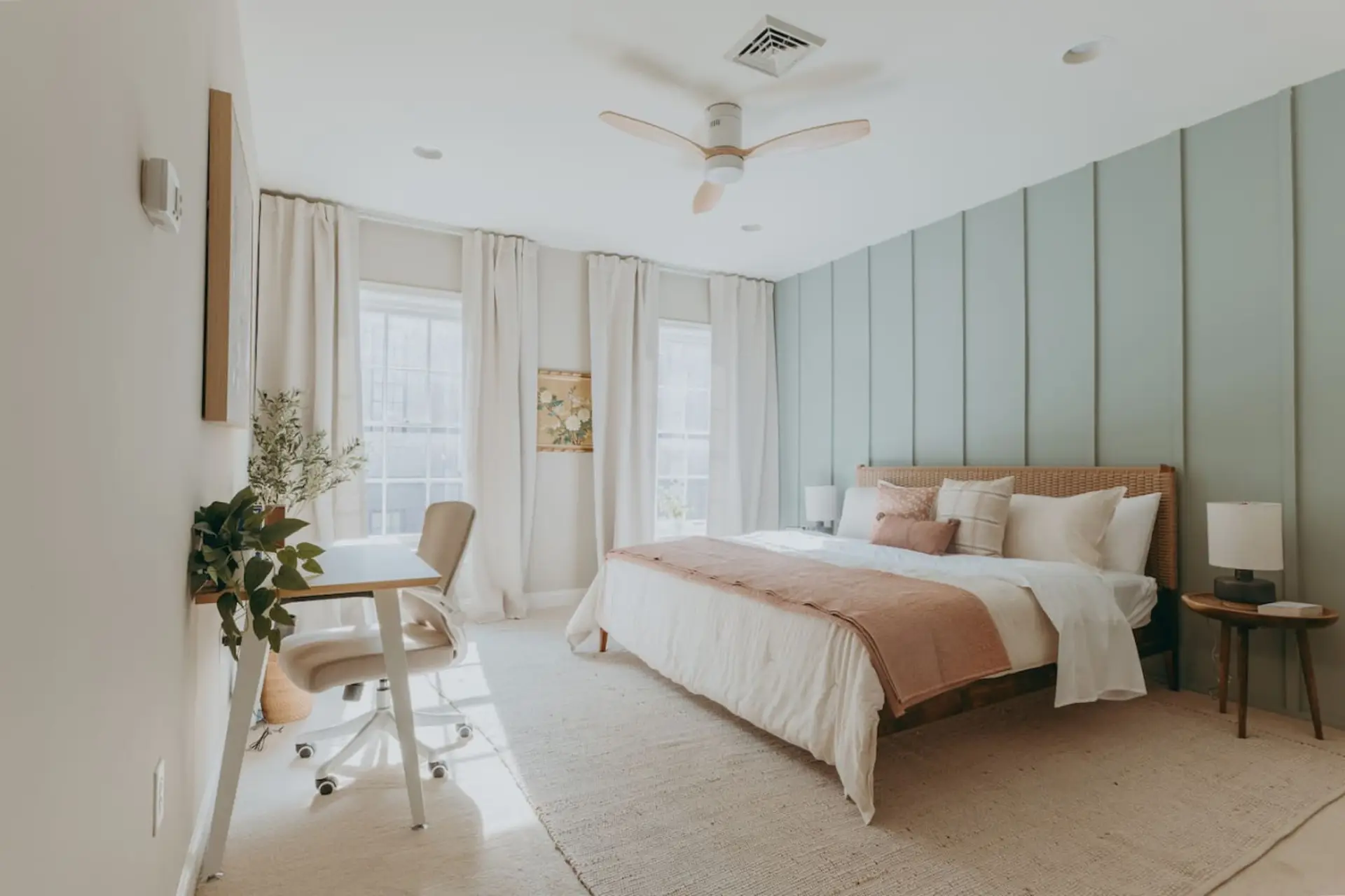 Minimalist bedroom with bedding, pillows, large windows with curtains, and a study table