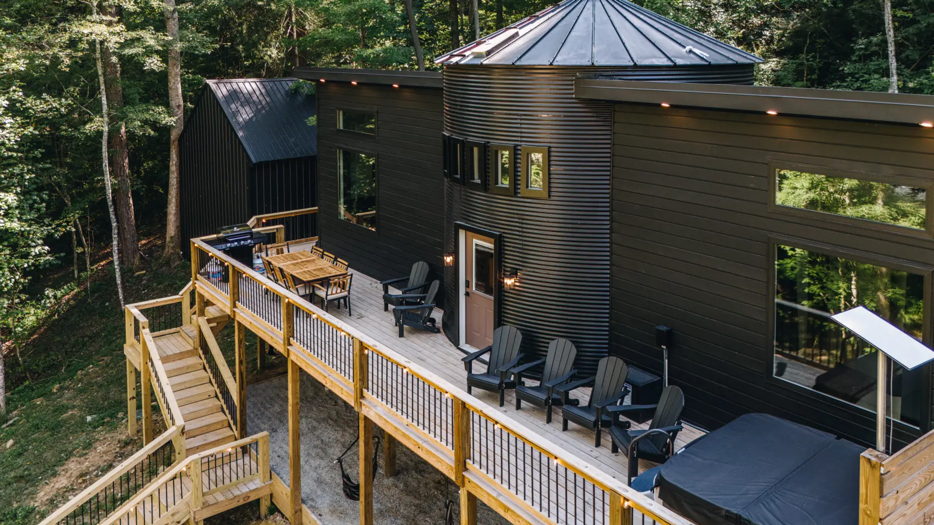 The Still's black silo silhouette rises above its 50-foot wraparound deck. Adirondack chairs, a hot tub, and the grill are all staged and ready for a fall weekend with the crew.