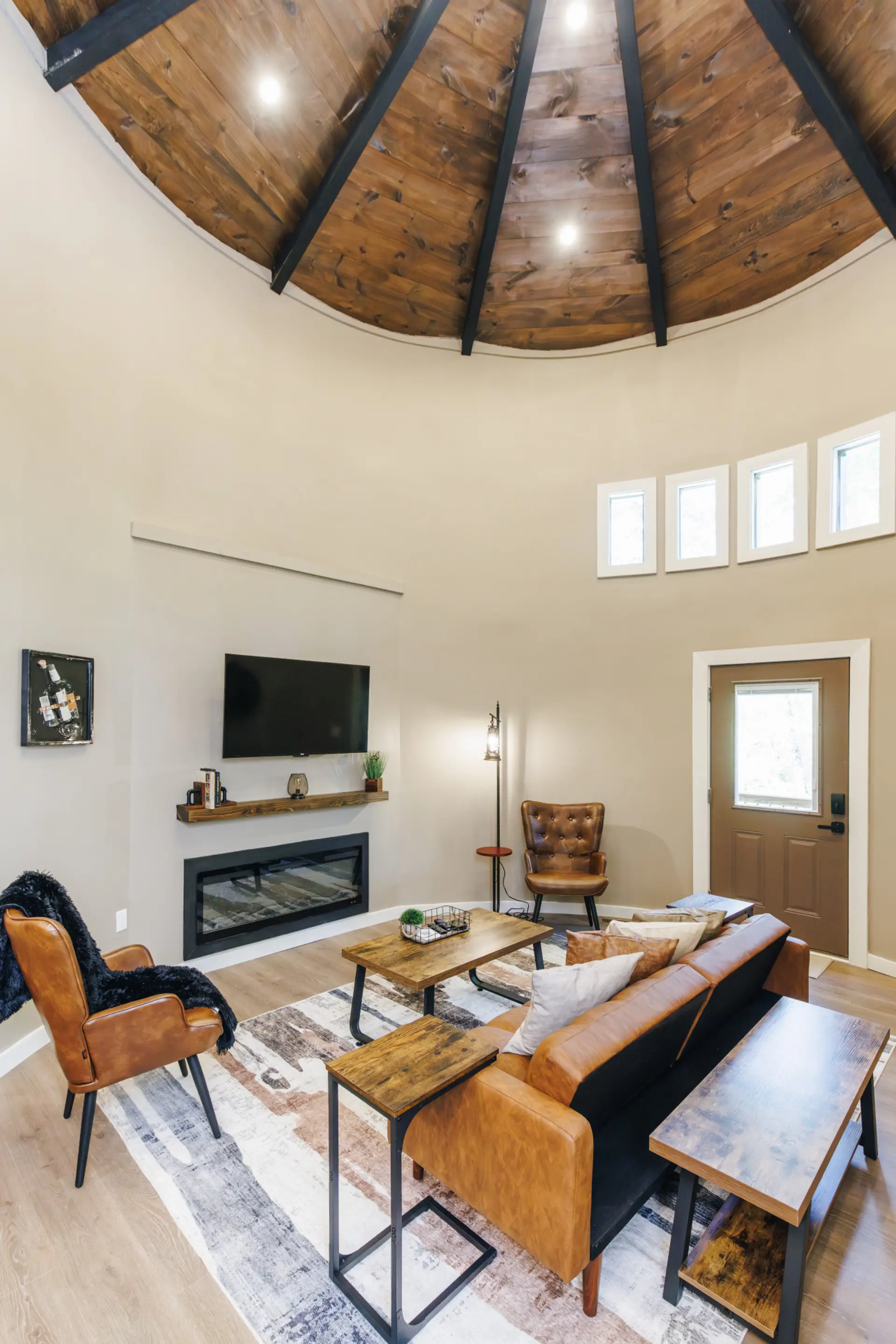 Vaulted ceilings and tall windows flood the silo living room with light. The electric fireplace, Smart TV, and leather seating make it the easy landing spot after a day on the trails.