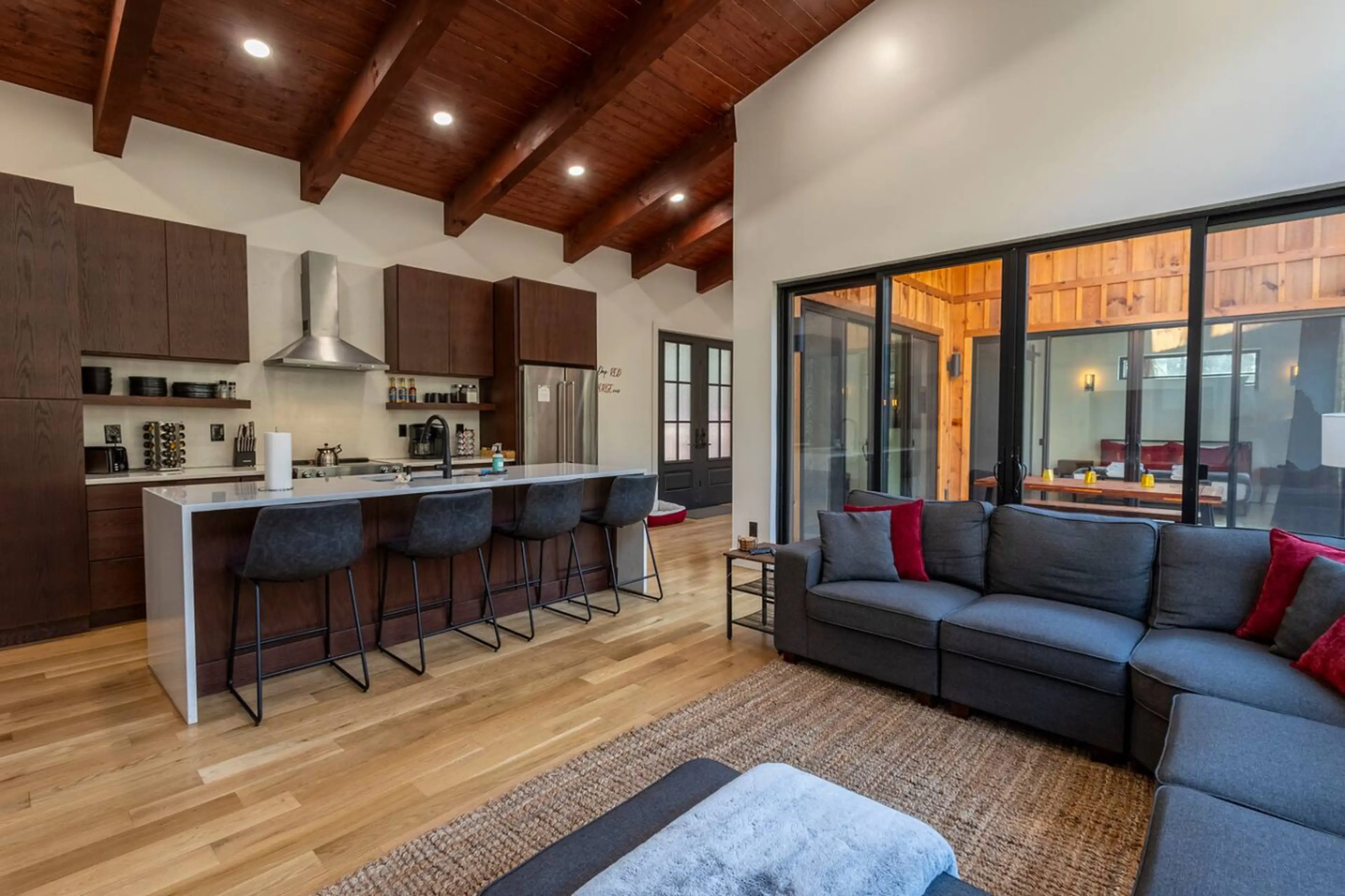 Gather in the heart of the cabin—an open living space with vaulted wood-beam ceilings, a modern kitchen, and cozy seating perfect for long talks or lazy mornings.