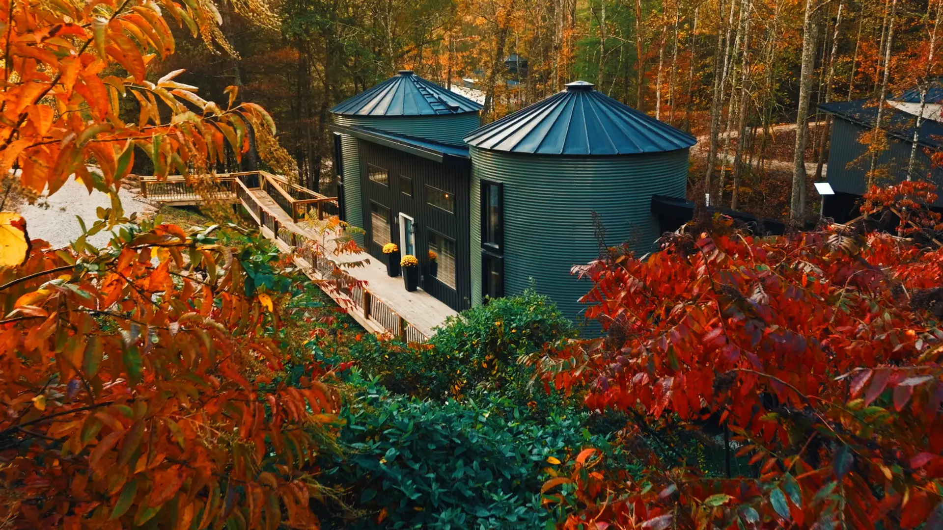 The Boone's twin silos rise out of blazing fall color — deep oranges and reds framing the wraparound deck. This is the Gorge in autumn, and it's yours for the weekend.