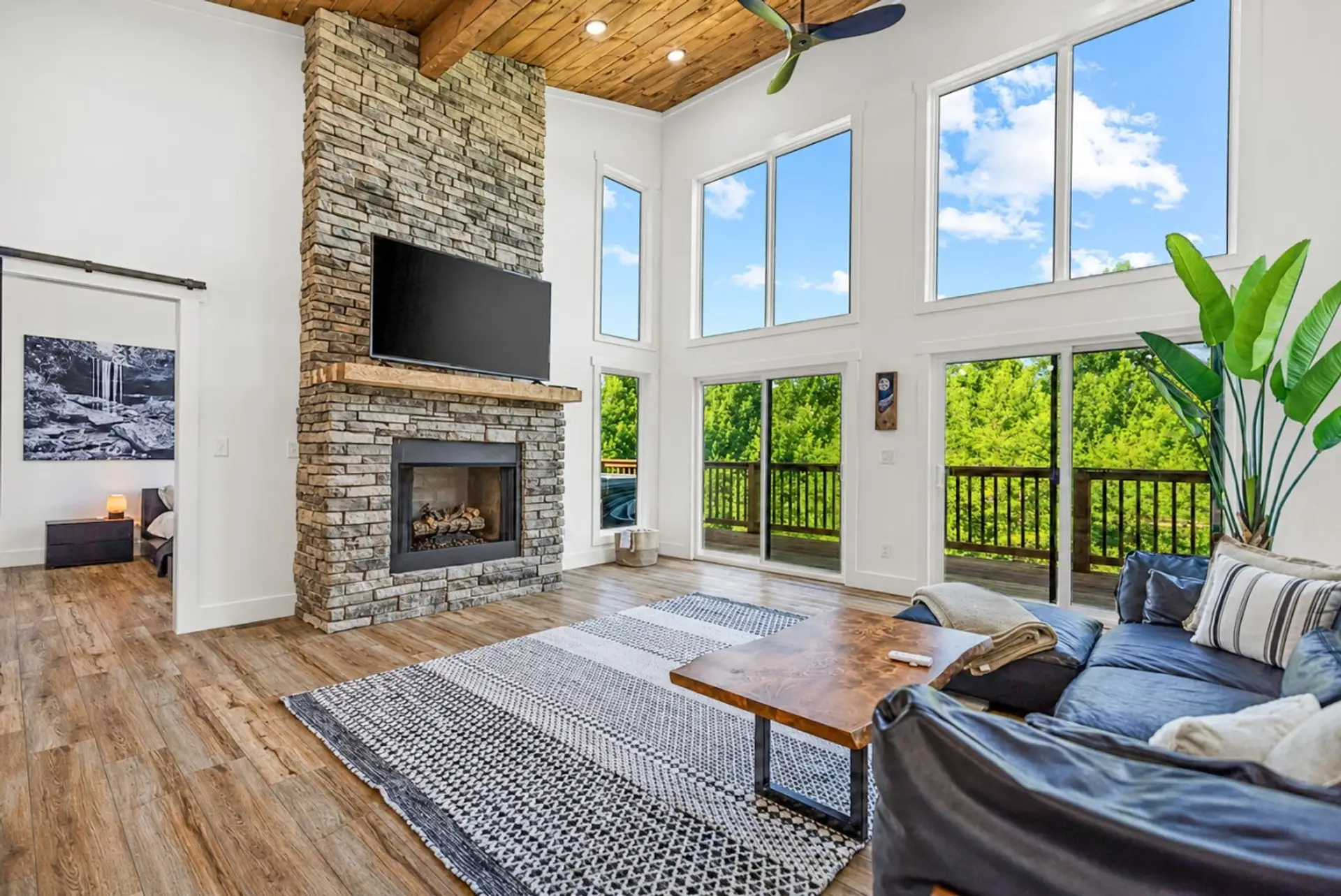 Spend a slow evening by the stone fireplace while tall windows frame peaceful forest views from the sofa