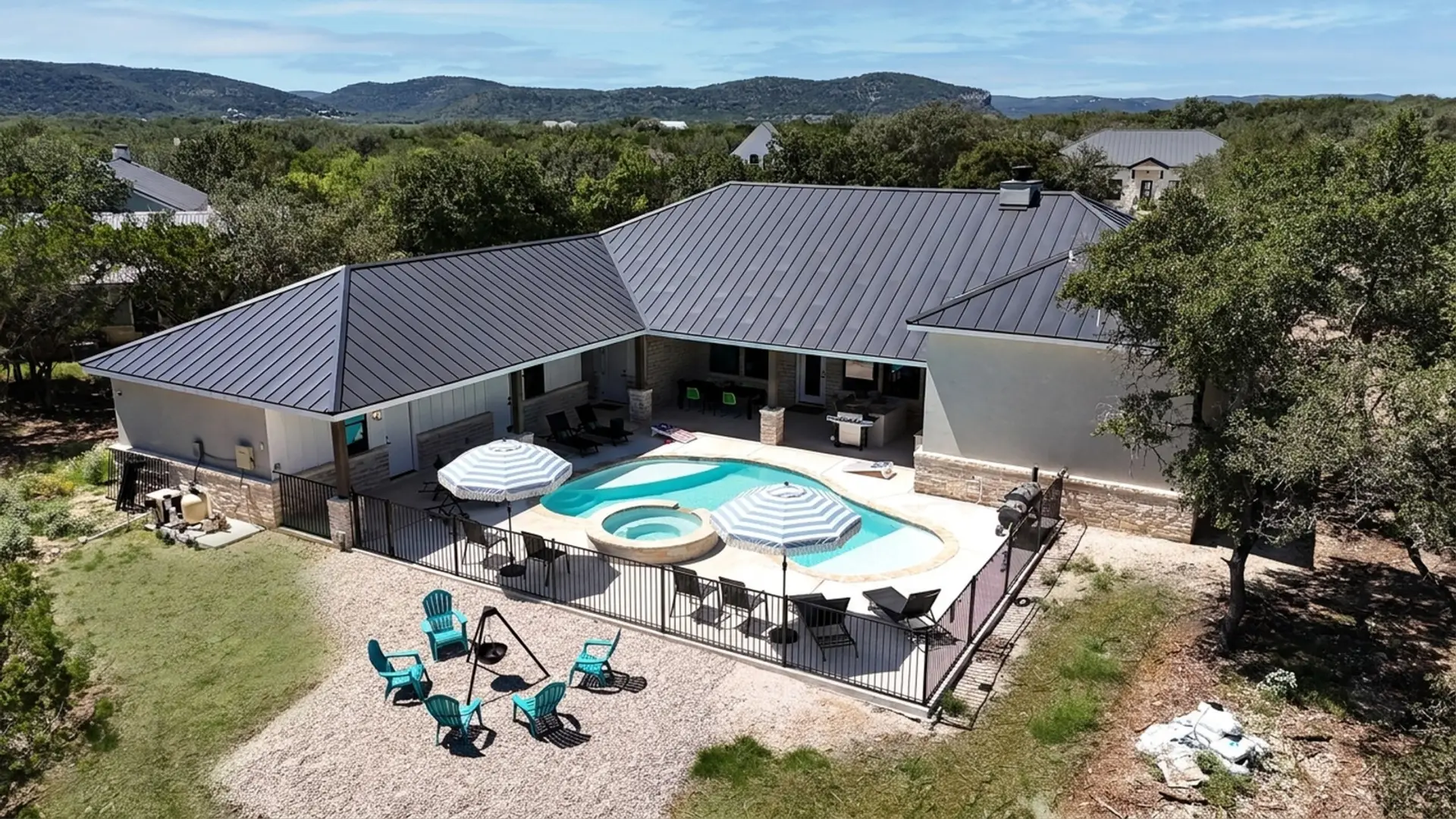 A bird's-eye view of the property showcasing a relaxing pool, hot tub, and fire pit area, perfect for outdoor fun with family or friends.