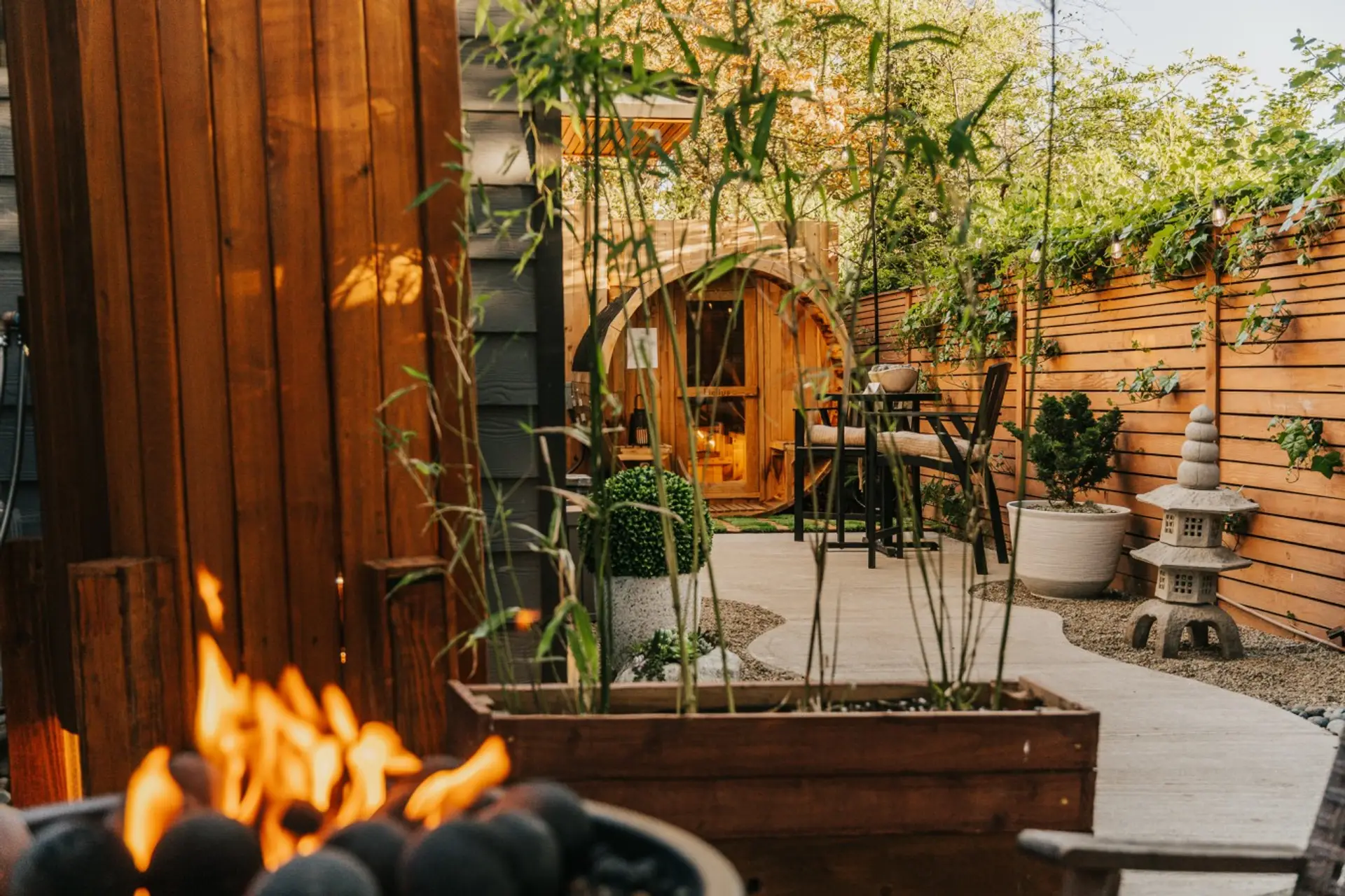 Private cedar barrel sauna nestled in a tranquil garden setting.