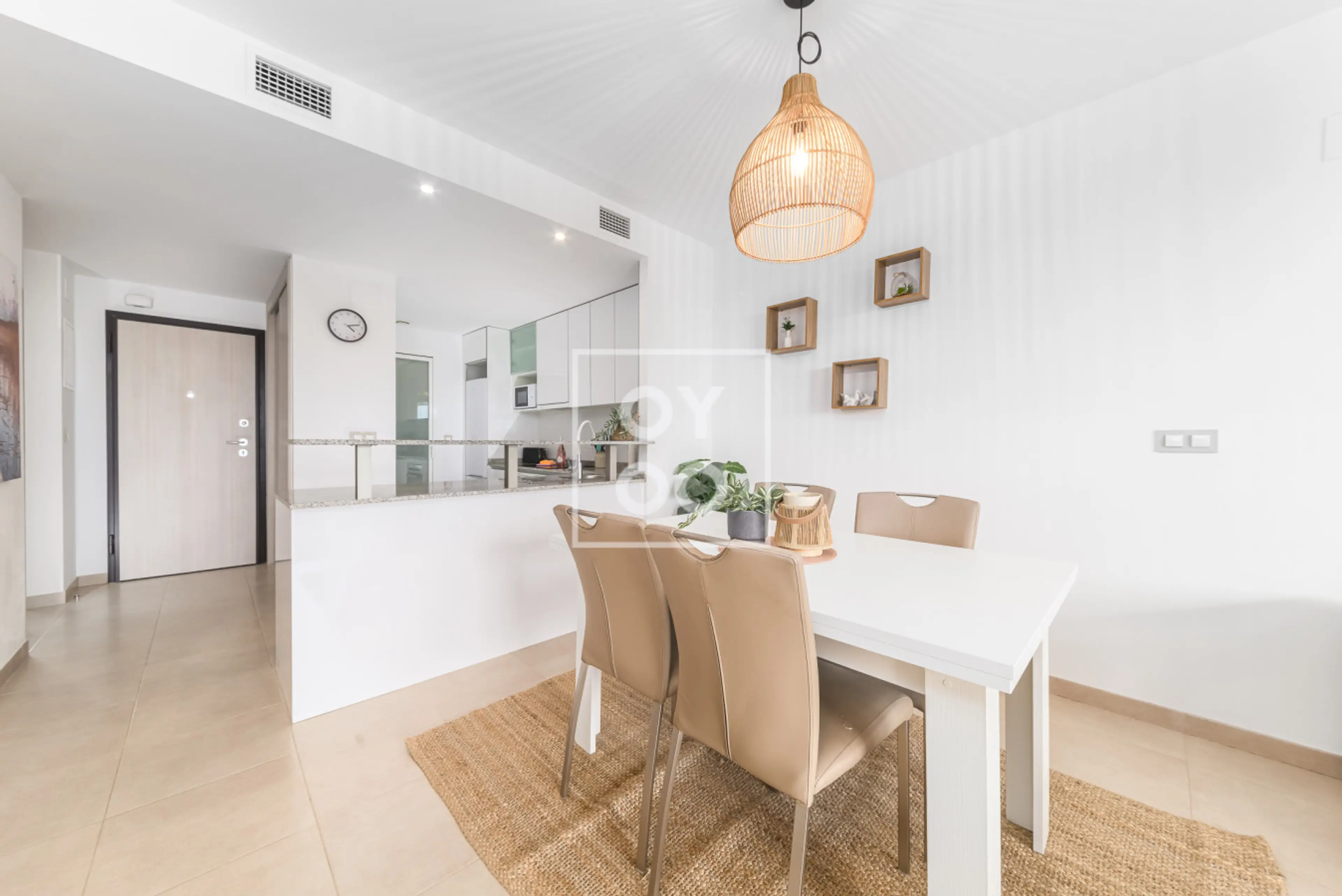 Connected dining area and kitchen via raised breakfast bar, featuring a white dining table on a jute rug. Pendant lighting and wall-mounted shelves highlight the seamless layout perfect for gatherings 🍽️💡