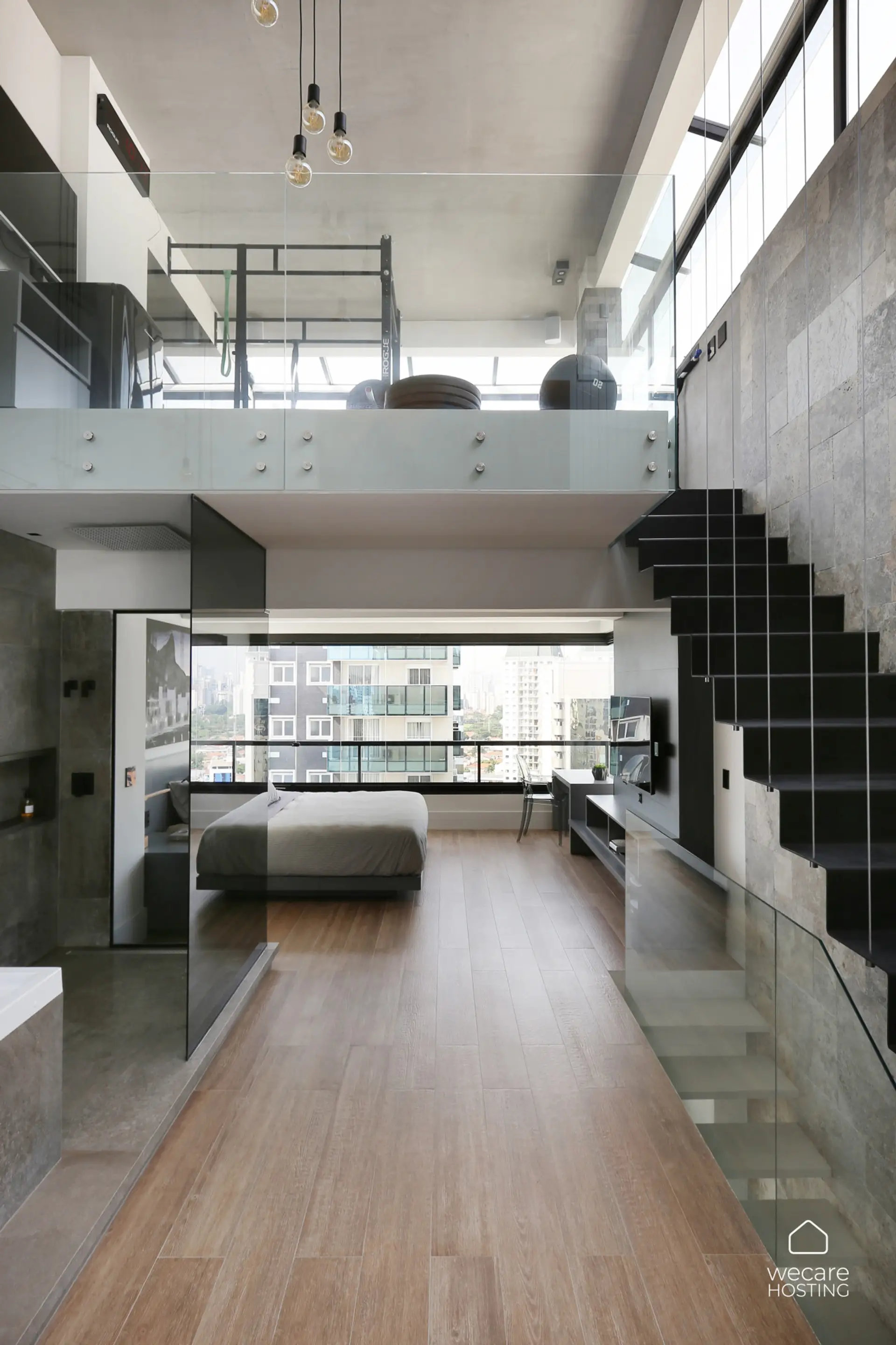 Loft moderno com pé-direito duplo, mezanino envidraçado e escada escultural em design industrial. O ambiente combina quarto, sala e home office em um espaço integrado, iluminado por amplas janelas com vista urbana.