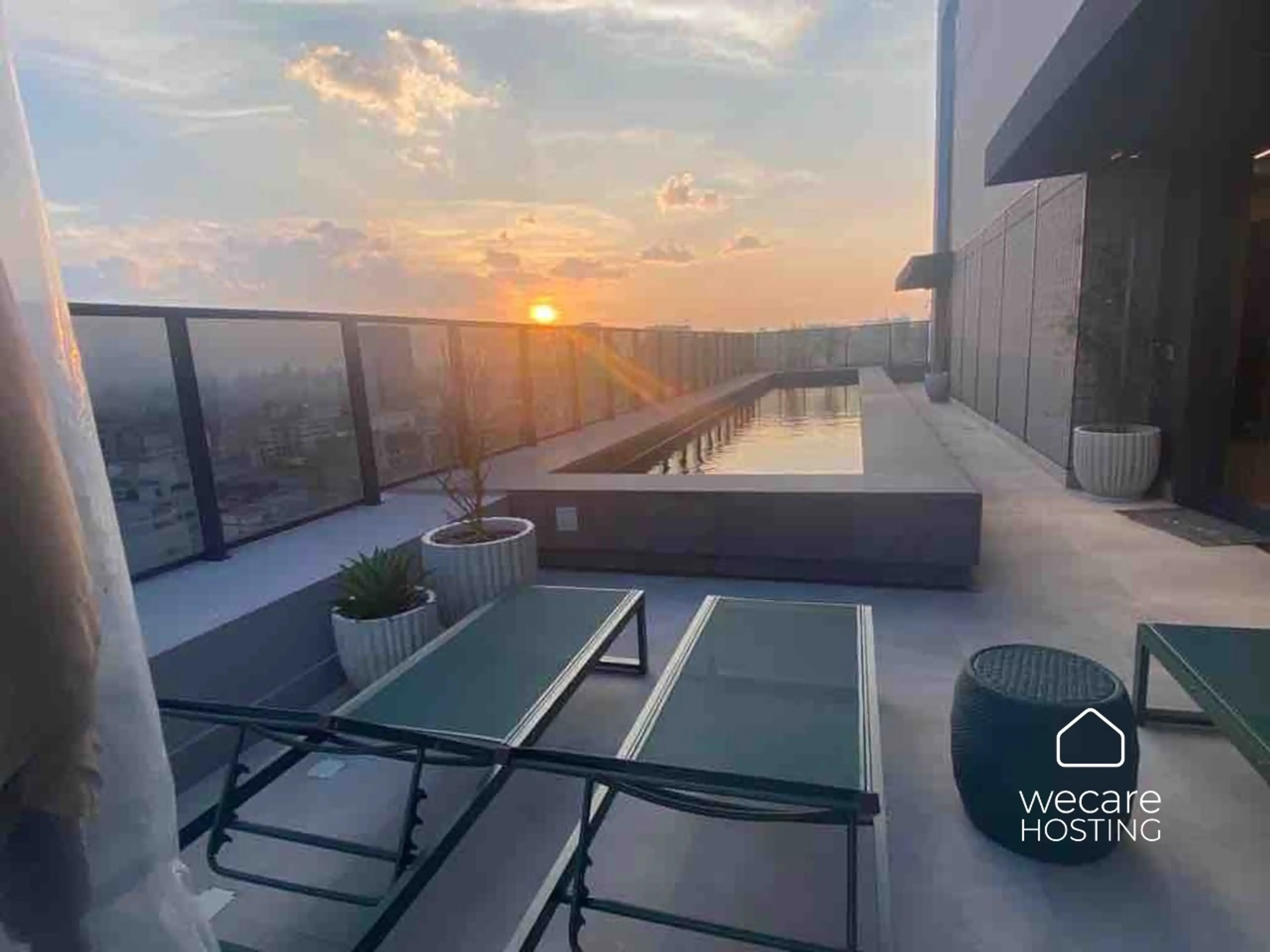 Área externa charmosa com piscina e espreguiçadeiras, perfeita para relaxar e aproveitar o pôr do sol com uma vista incrível da cidade.