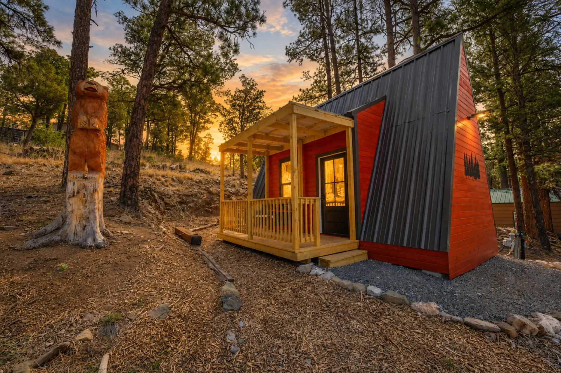Cozy A-frame cabin tucked among the pines with a peaceful porch and glowing sunset views.