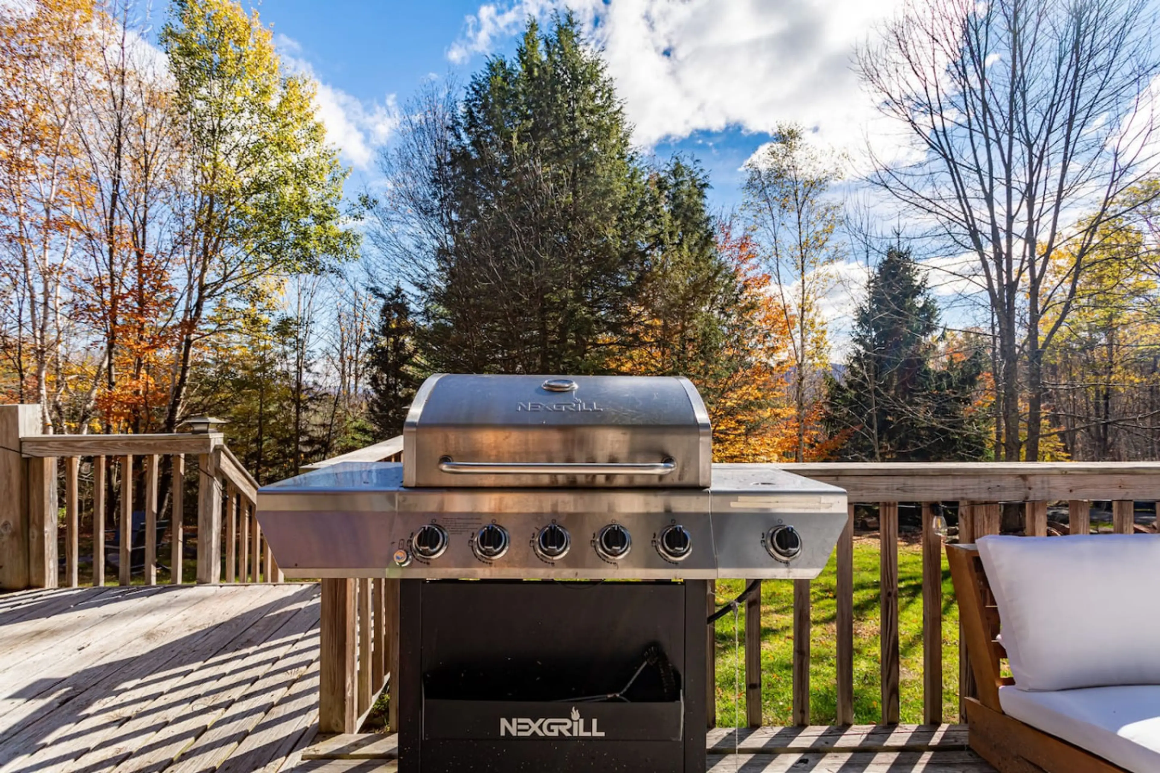 Gas grill on lower deck with fall foliage backdrop