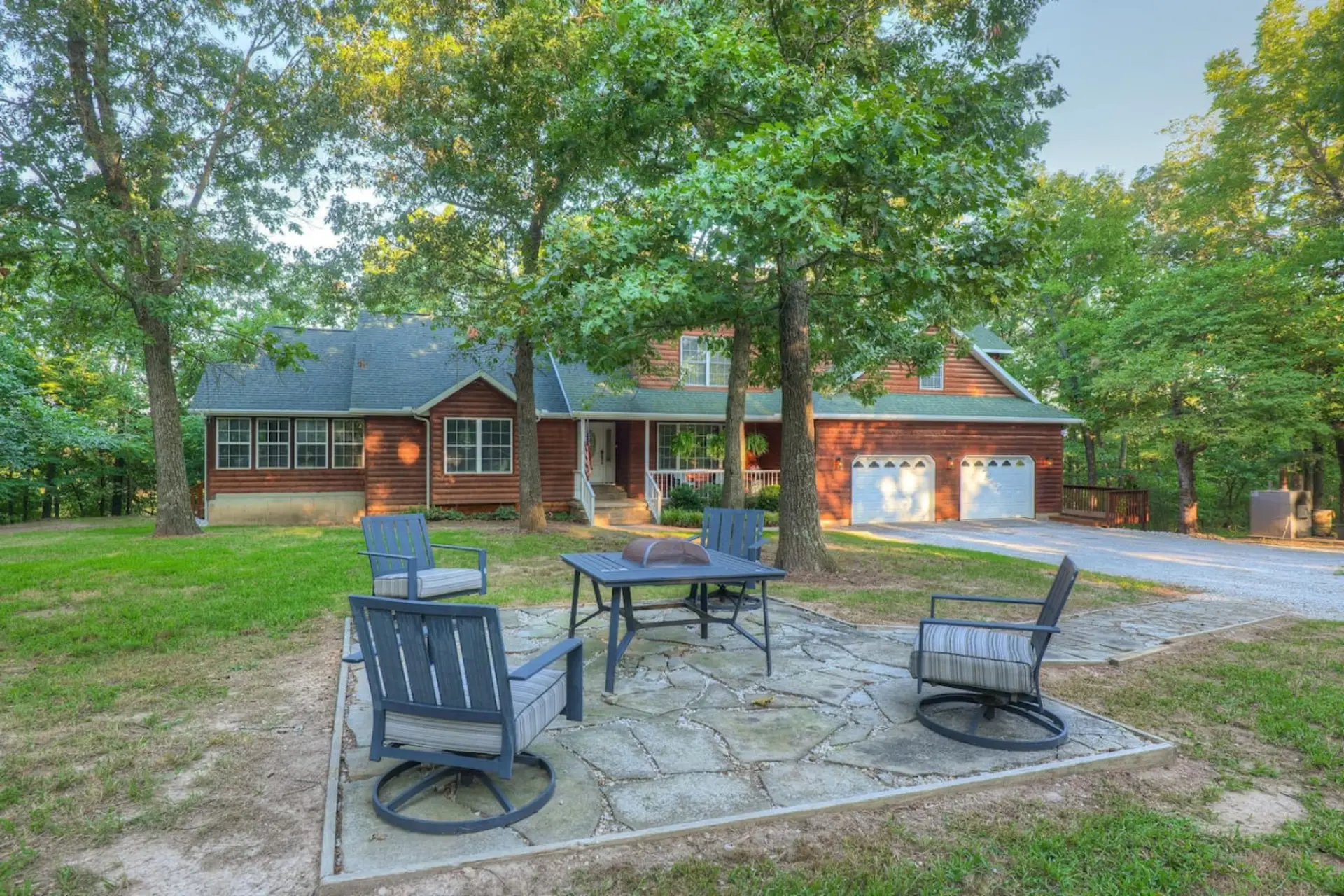 Find peace and comfort in this lovely house, featuring a vast grassy area and a relaxing outdoor seating space amidst the trees.