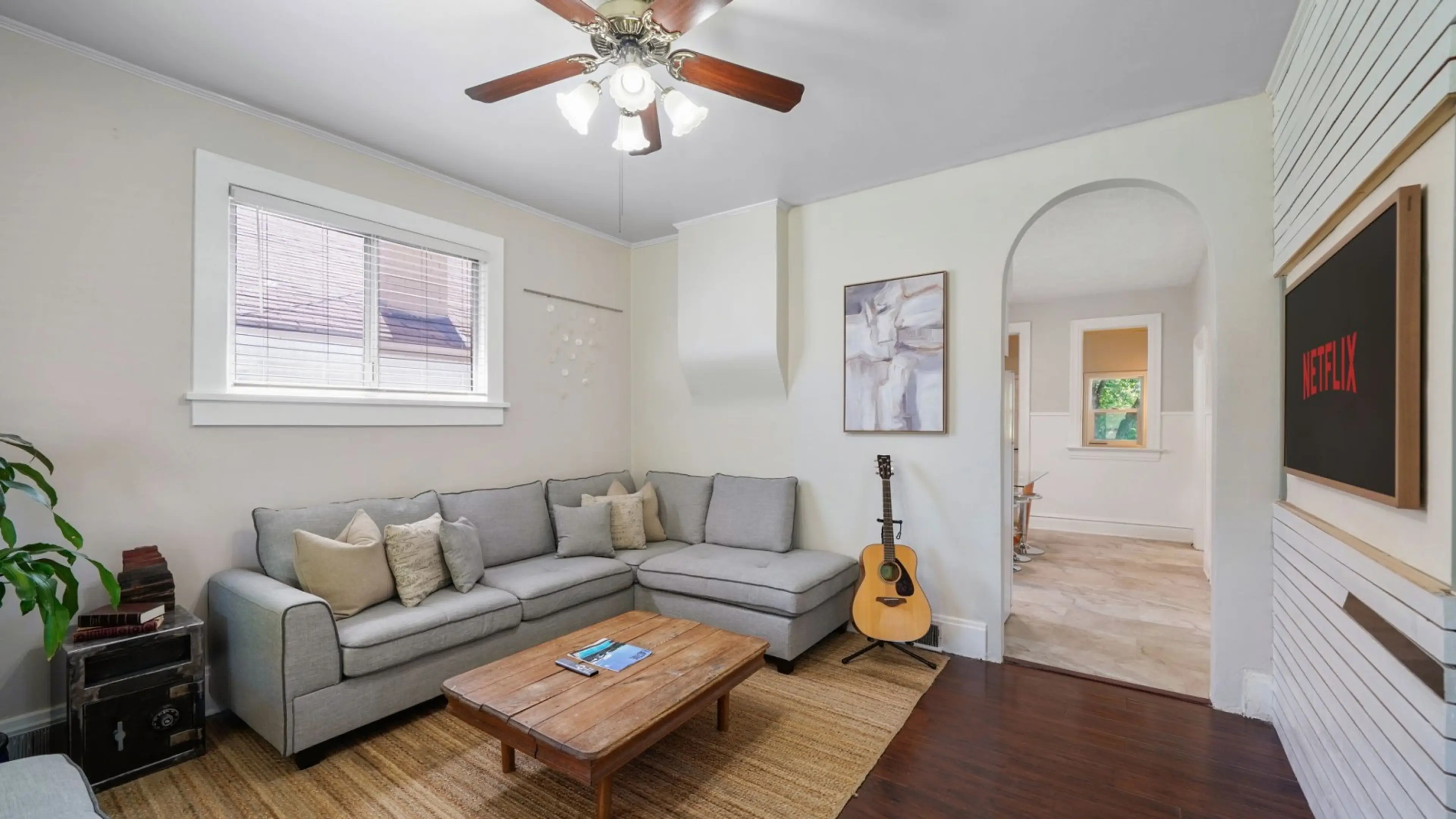 A closer look at the cozy sectional and flat-screen TV. The open arched doorway leads straight into the kitchen, keeping the floor plan connected and social.