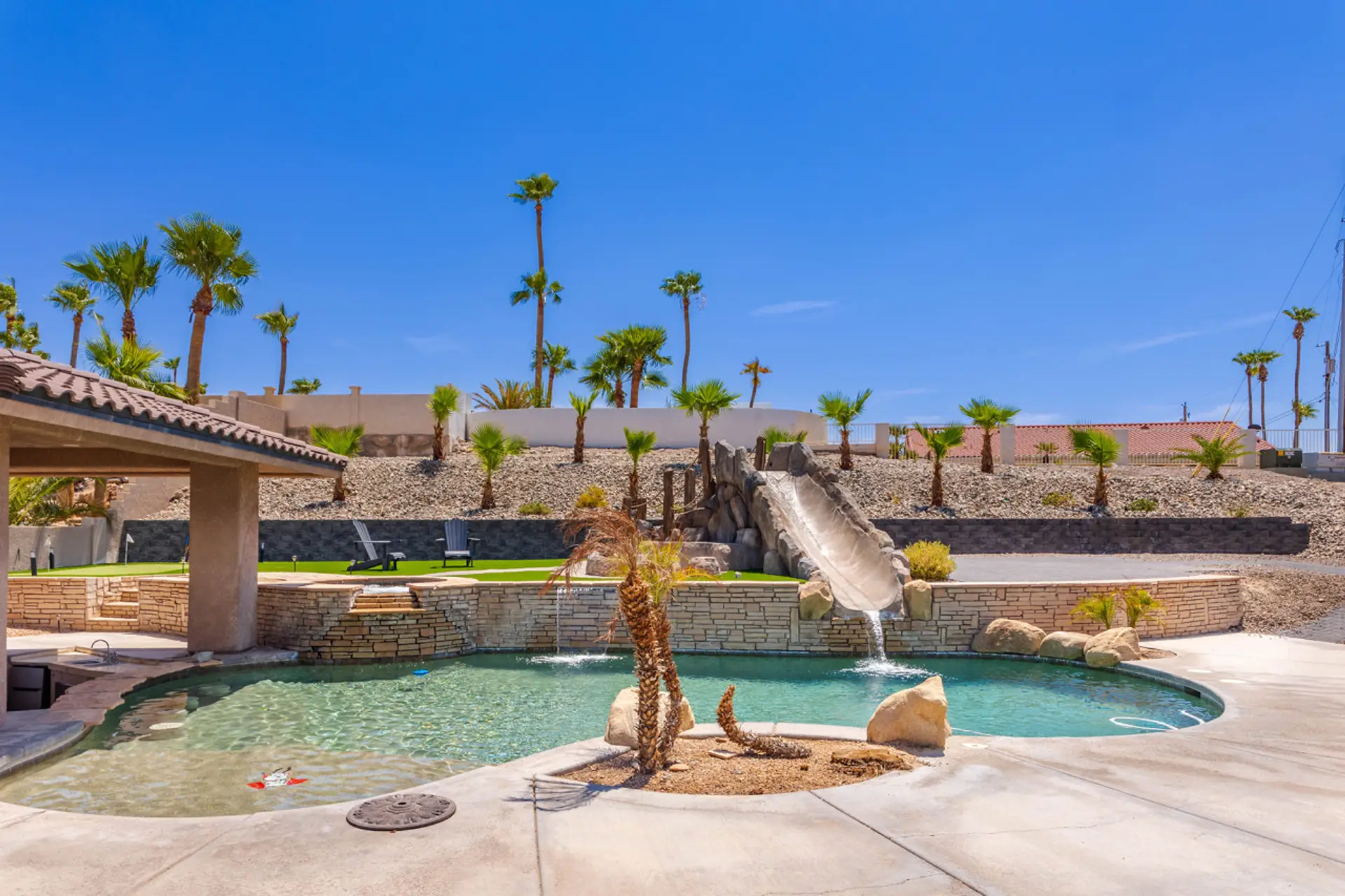 Resort-style backyard oasis featuring a sparkling pool, thrilling waterslide, and desert-inspired landscaping