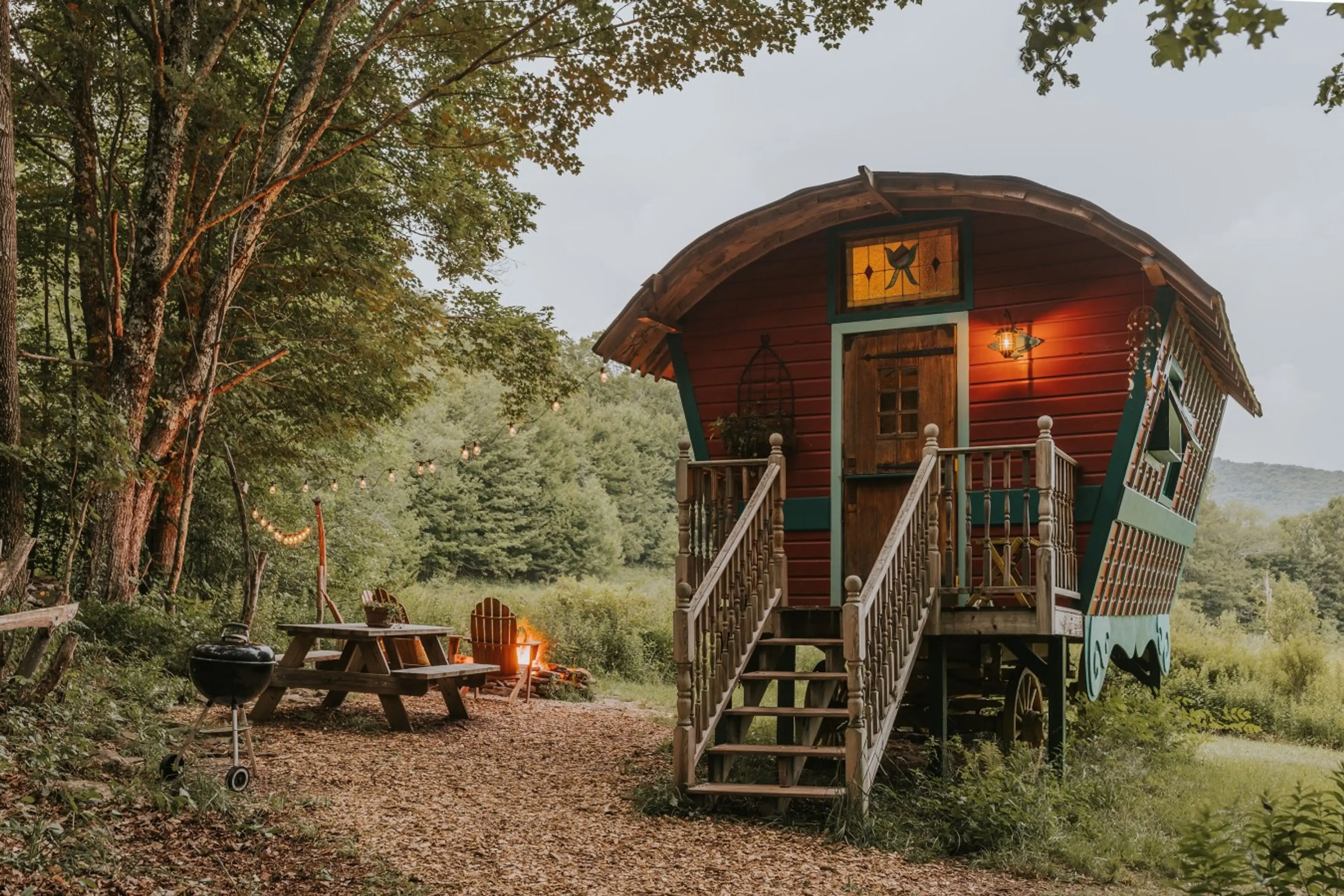 A handcrafted cabin built on original wagon wheels, surrounded by forest and meadow.
