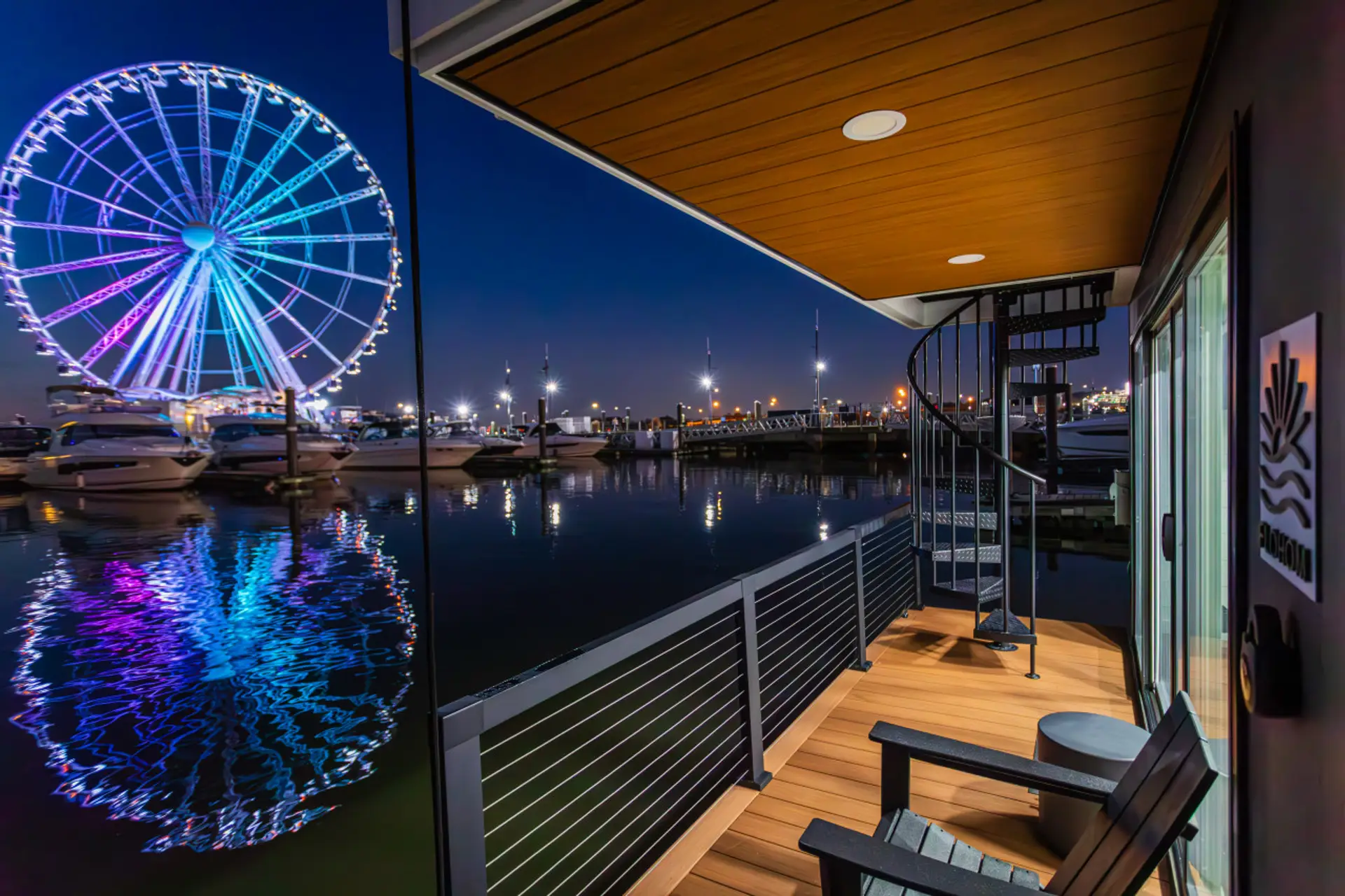 Aft deck with spiral staircase to the rooftop and an unobstructed nighttime view of the Capital Wheel glowing in vibrant colors over National Harbor.