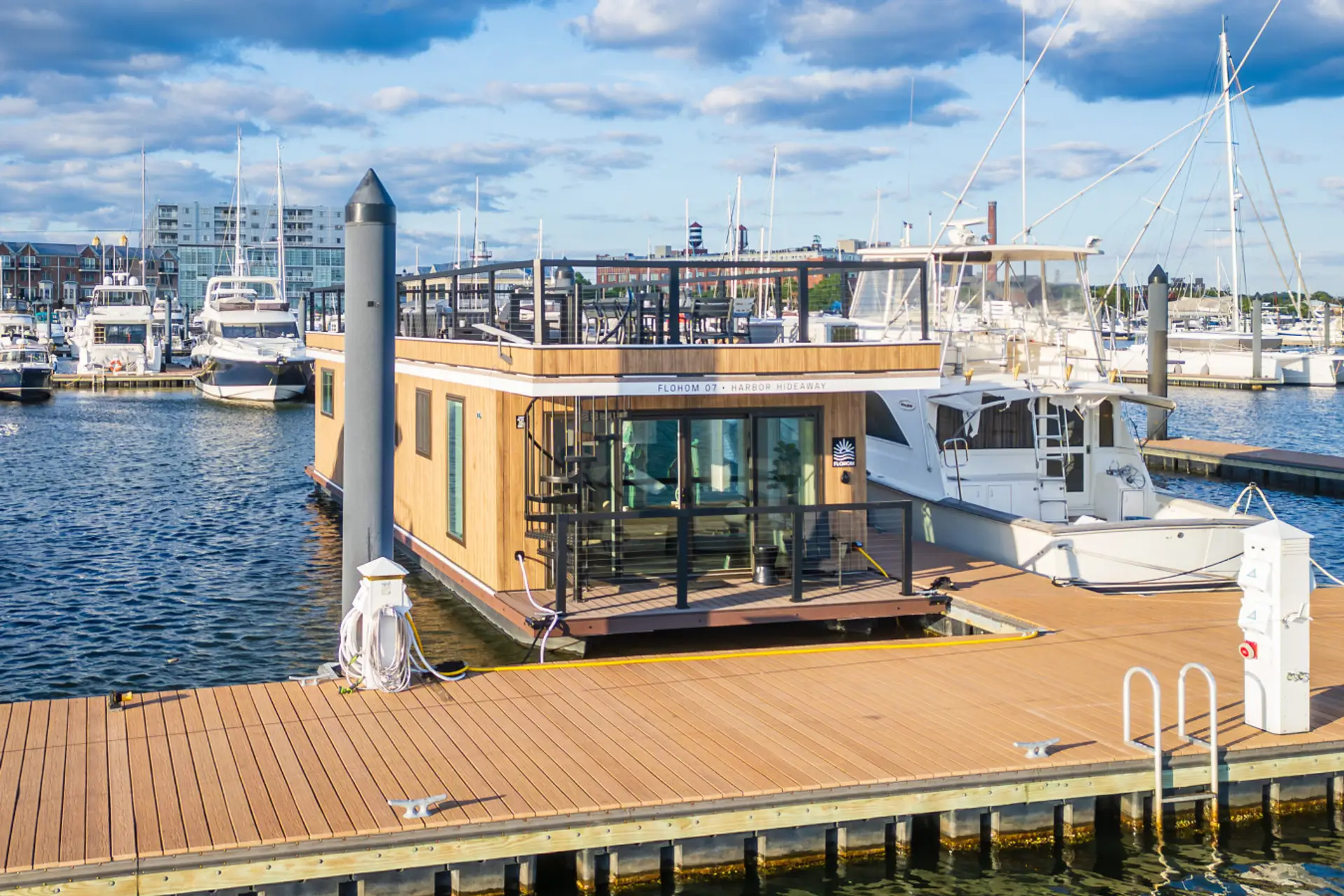 Harbor Hideaway docked at Lighthouse Point Marina with sailboats and yachts lining the slips and the Canton waterfront skyline behind.