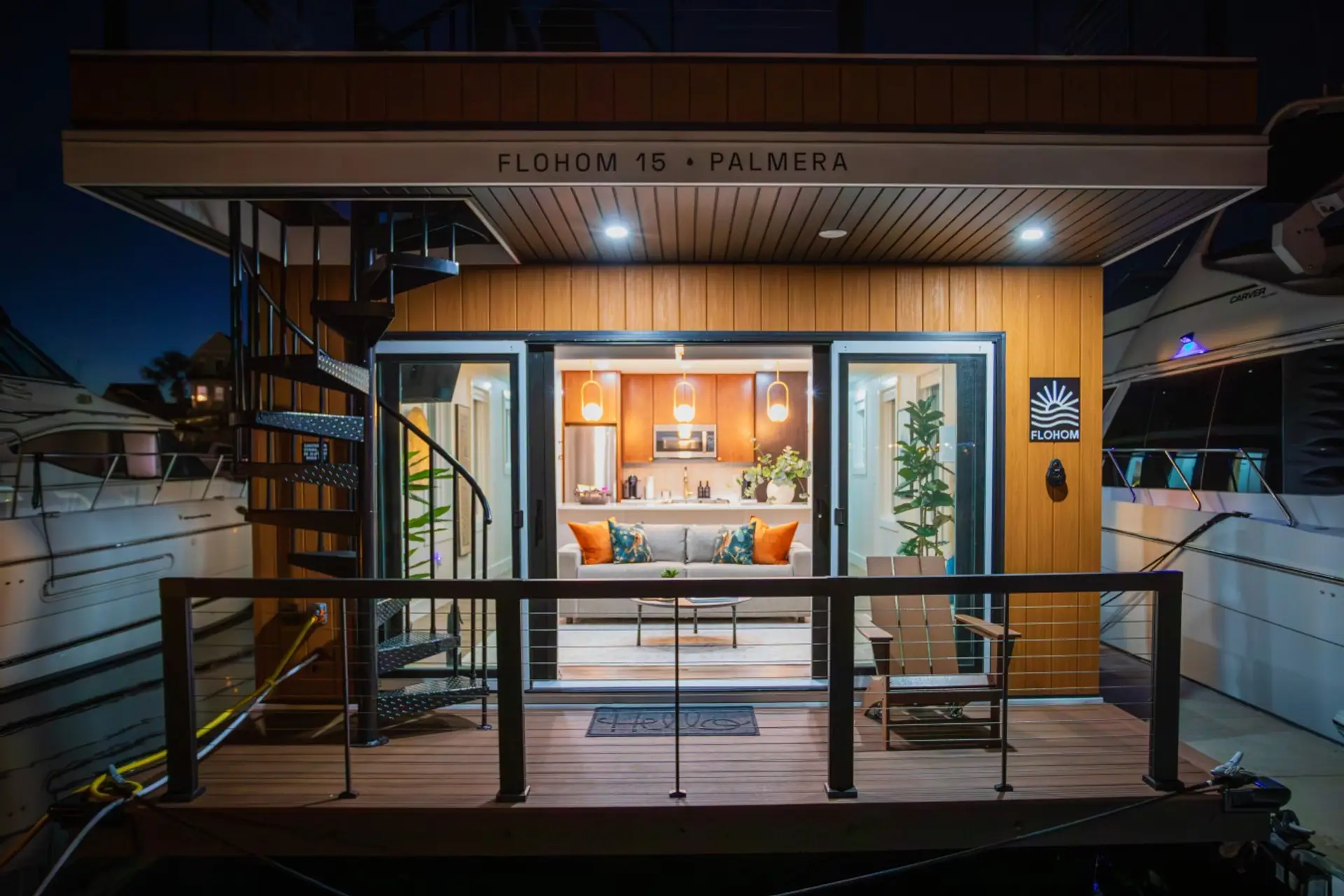 Front-facing twilight view of Palmera with the sliding glass doors open, the warm interior on full display, the spiral staircase leading to the rooftop
