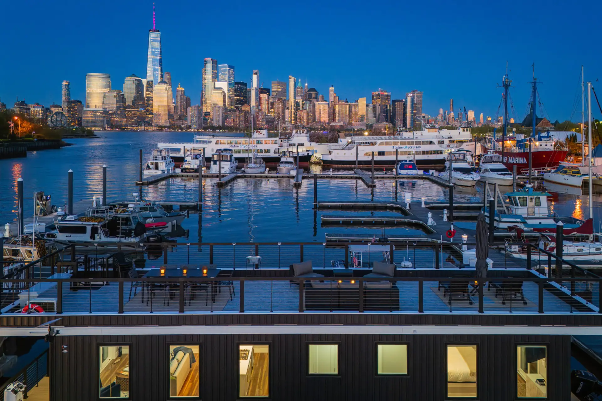 Rooftop deck at blue hour, Liberty Landing Marina. One World Trade and the full Manhattan skyline directly across the Hudson