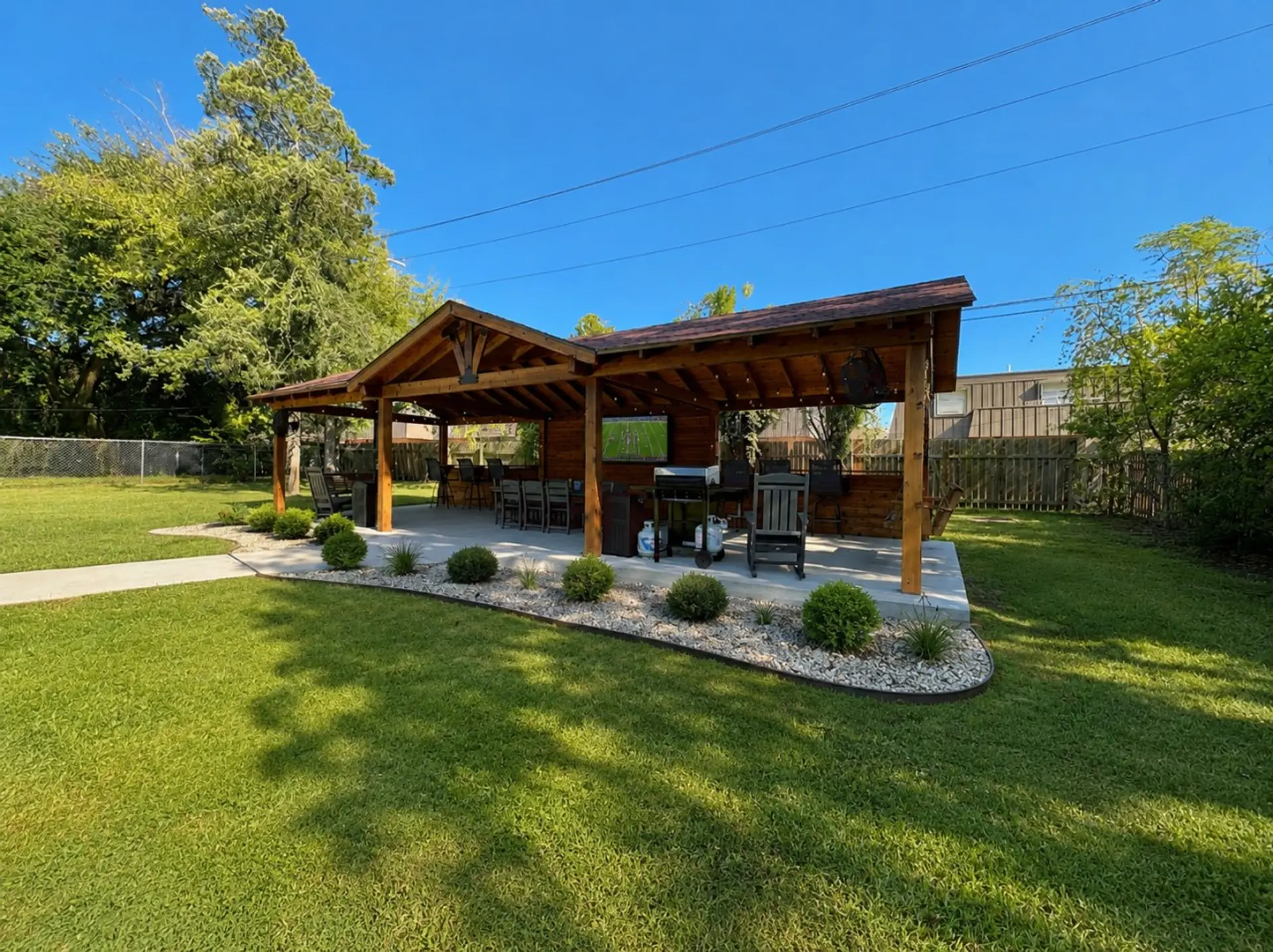 Relax or entertain under the backyard pavilion, equipped with seating, TV, and grill.