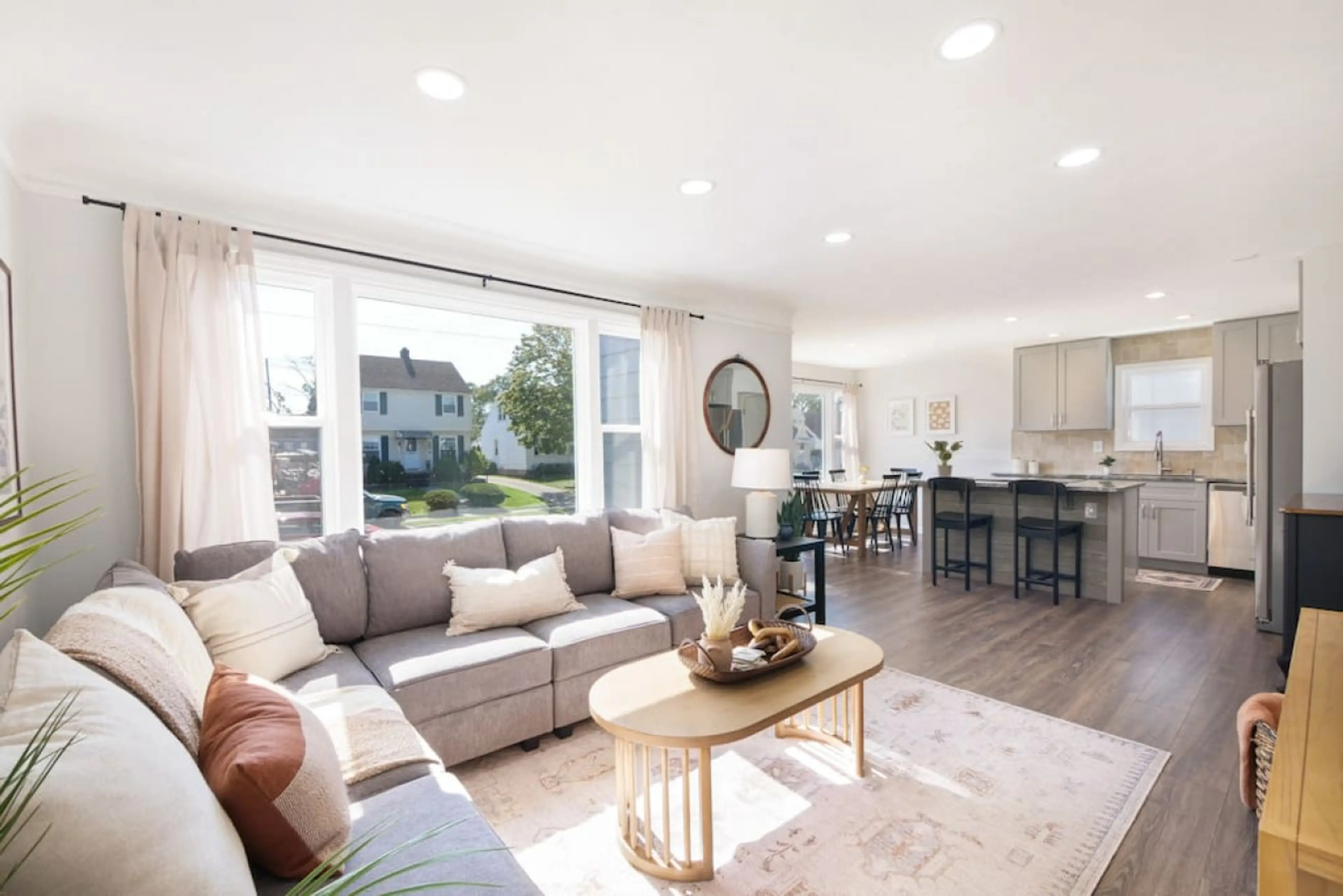 Open-plan living area bathed in natural light, anchored by a plush sectional and layered rug—effortless flow from the cozy lounge to the dining nook and kitchen beyond. 🛋️🌞