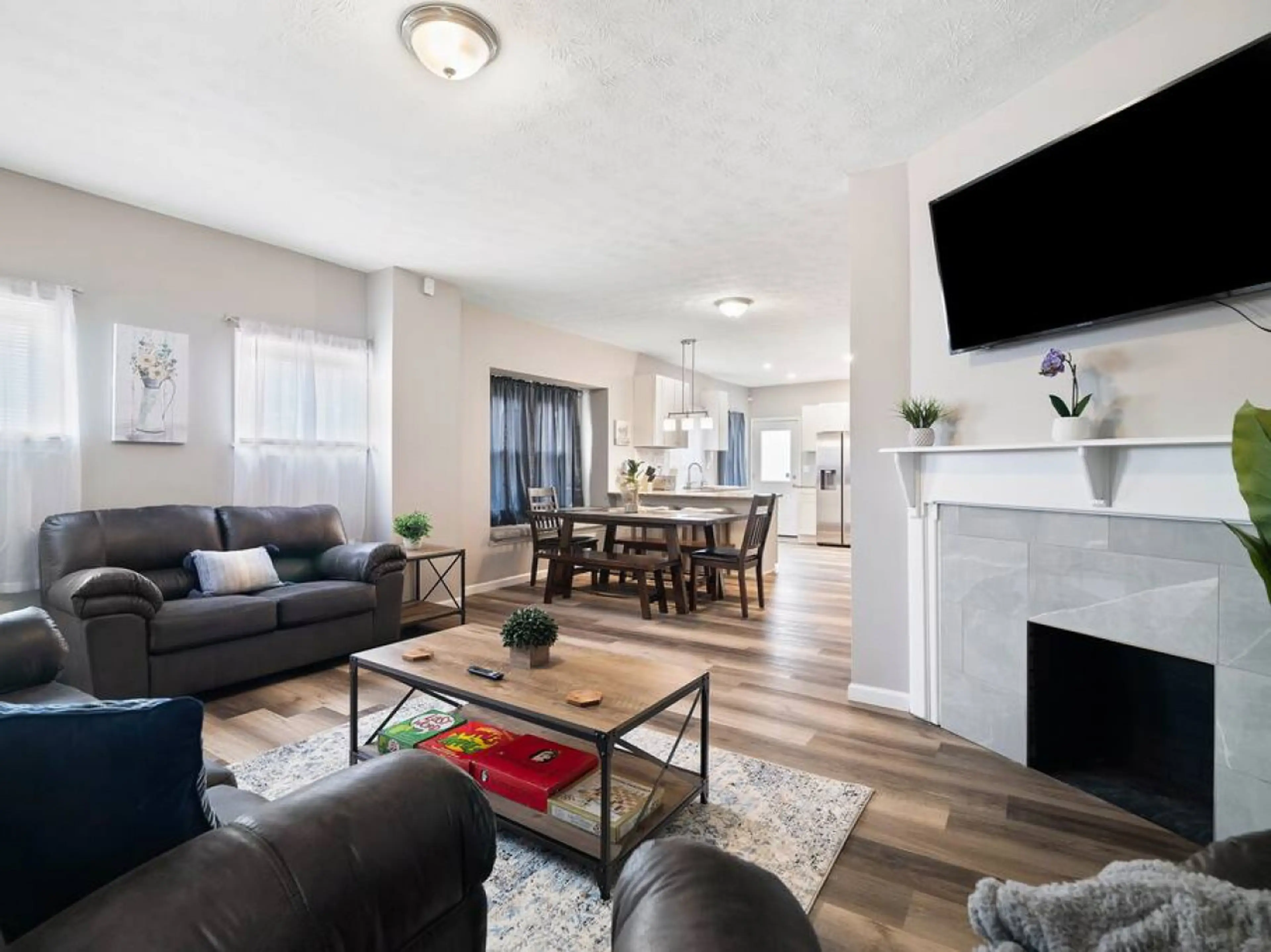 Step into this open-concept living area with cozy leather sofas, a stylish coffee table, and a modern fireplace topped by a wall-mounted TV. The space flows seamlessly into a dining area and bright kitchen for effortless entertaining! 🛋️🔥🍽️