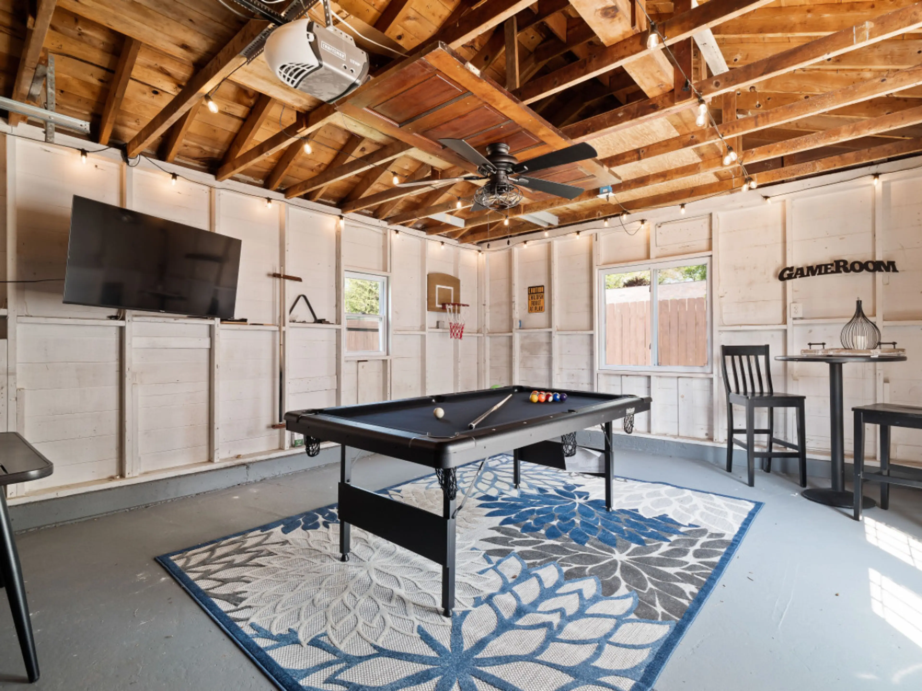 Game night ready! 🎯 This stylish garage hangout features a pool table, mounted TV, bar seating, string lights & a cozy vibe for hours of indoor fun. Perfect for rainy days or evening chill-outs! 🎱📺