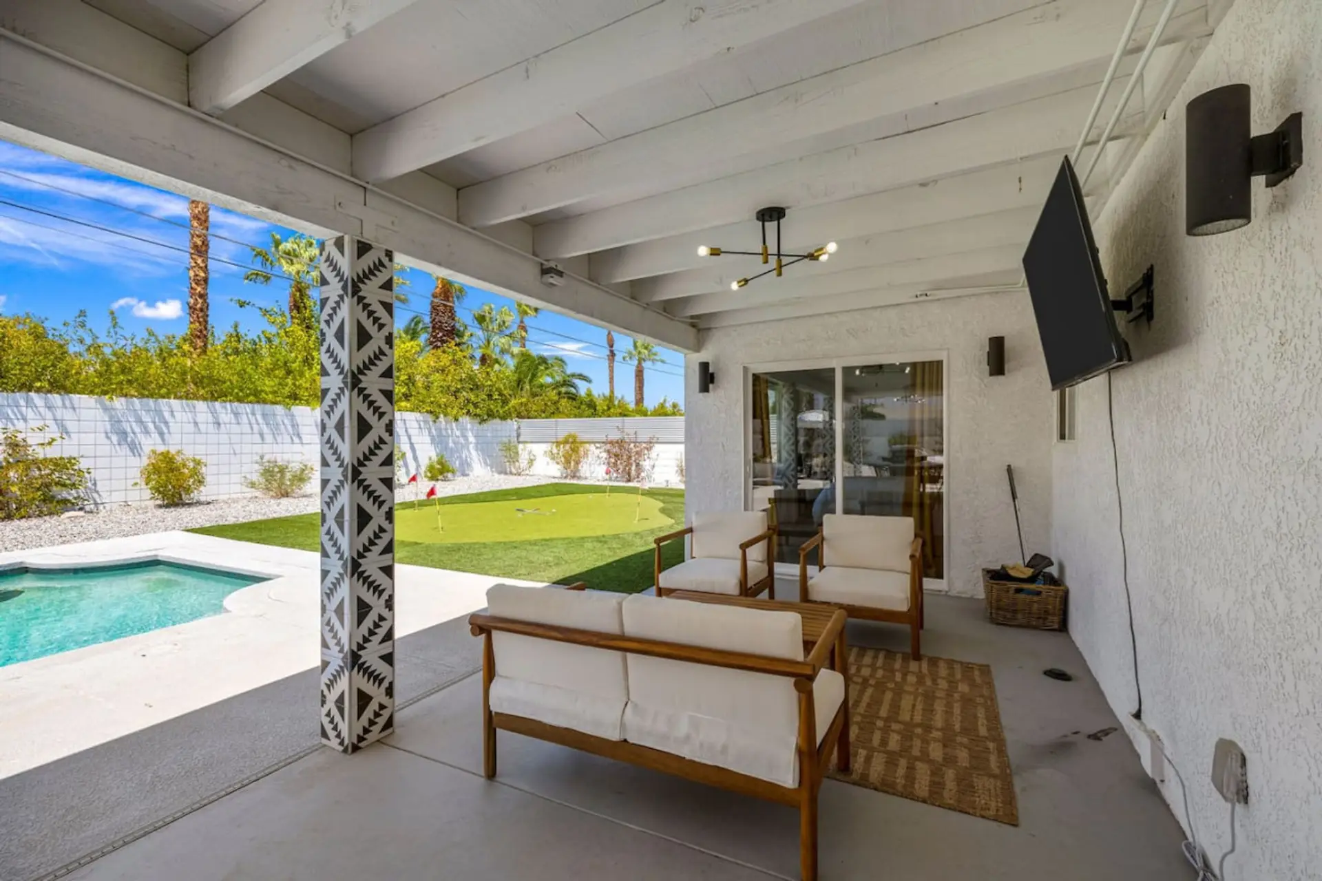 Poolside covered lounge w/ seating and TV, blending indoor comfort w/ outdoor living.