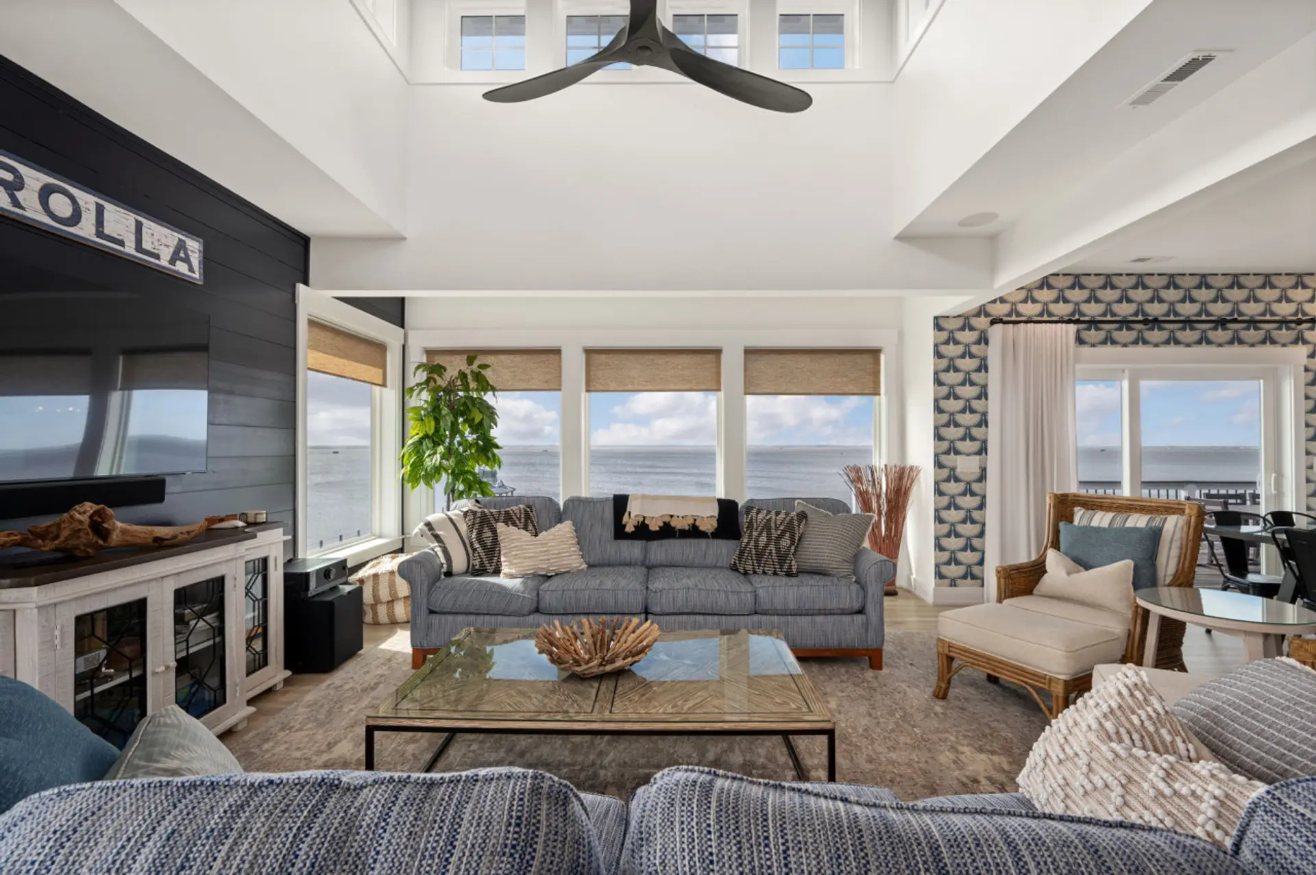 Bright living room w/ plush seating, coastal accents & large windows that fill the space with natural light.