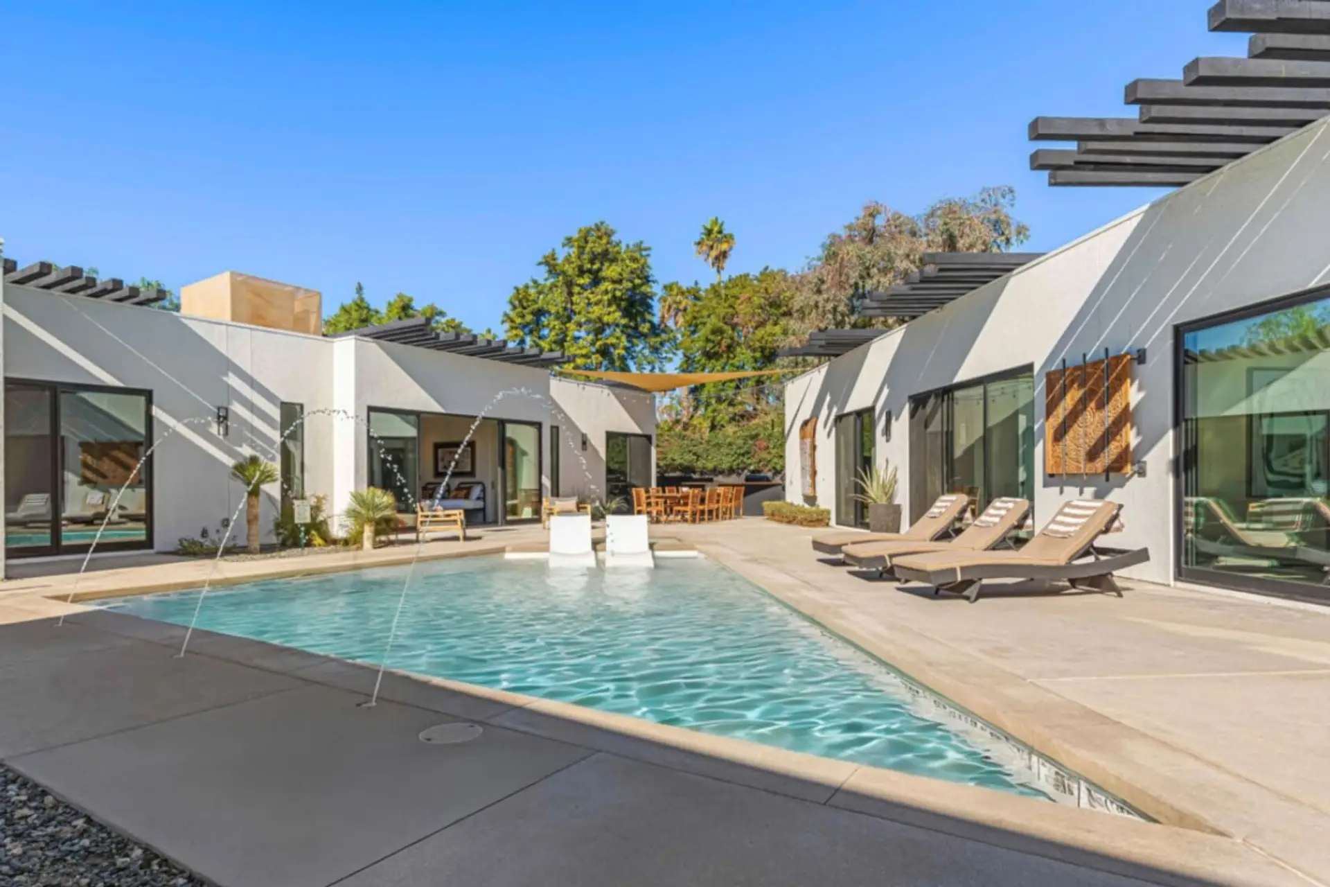 Walled pool courtyard w/ lounge chairs, palm views & the home's glass-wall wing for sunny afternoons.