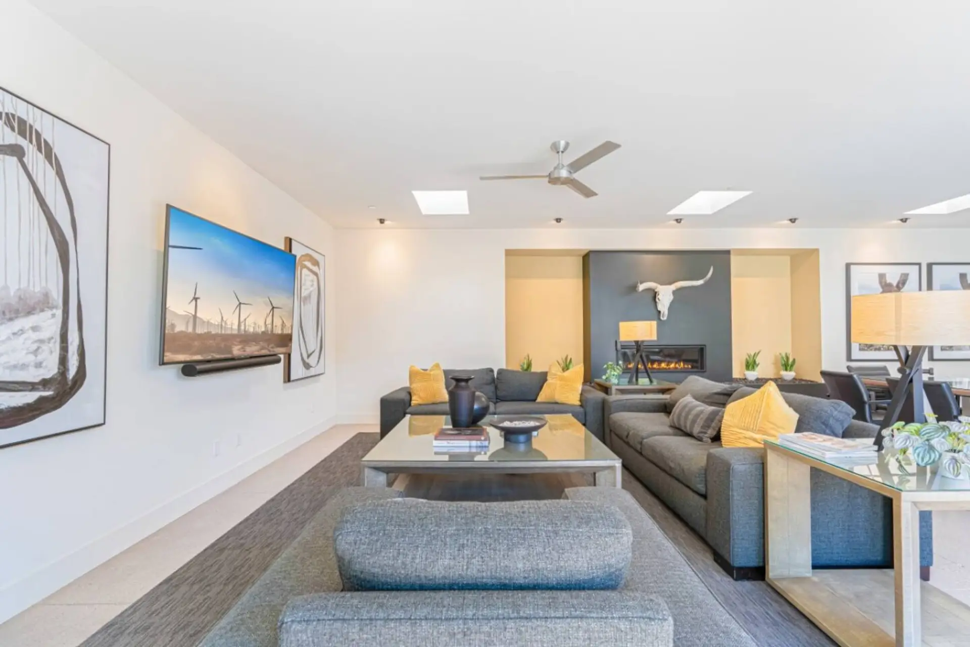 Open living room w/ wall-mounted TV, deep sectional & ottoman for easy movie nights.