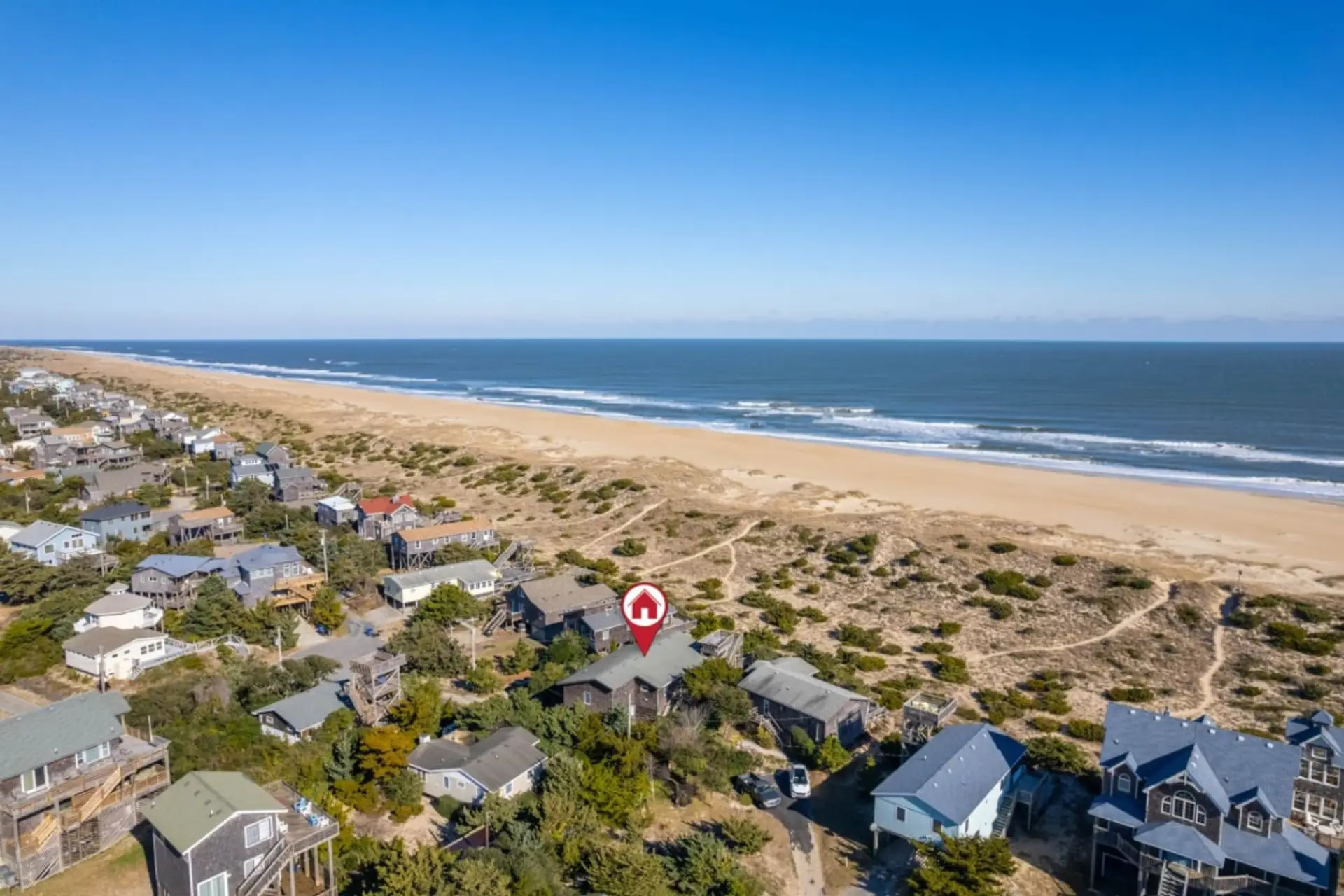 Sweeping coastal view over sandy shores, rooftops & endless ocean horizons.