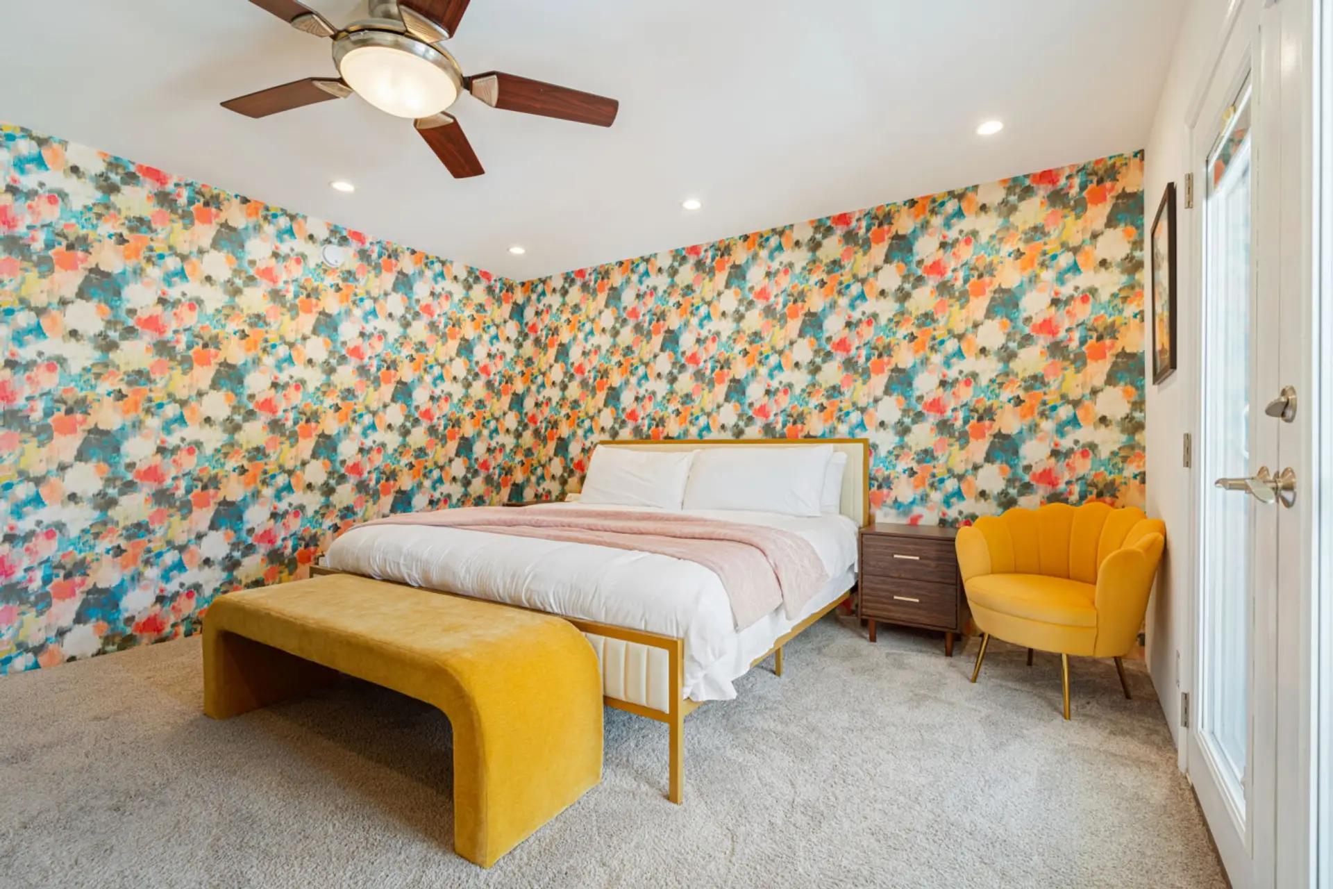 Cheerful bedroom w/ bold wallpaper, cozy bedding, & warm tones that make mornings feel happy.