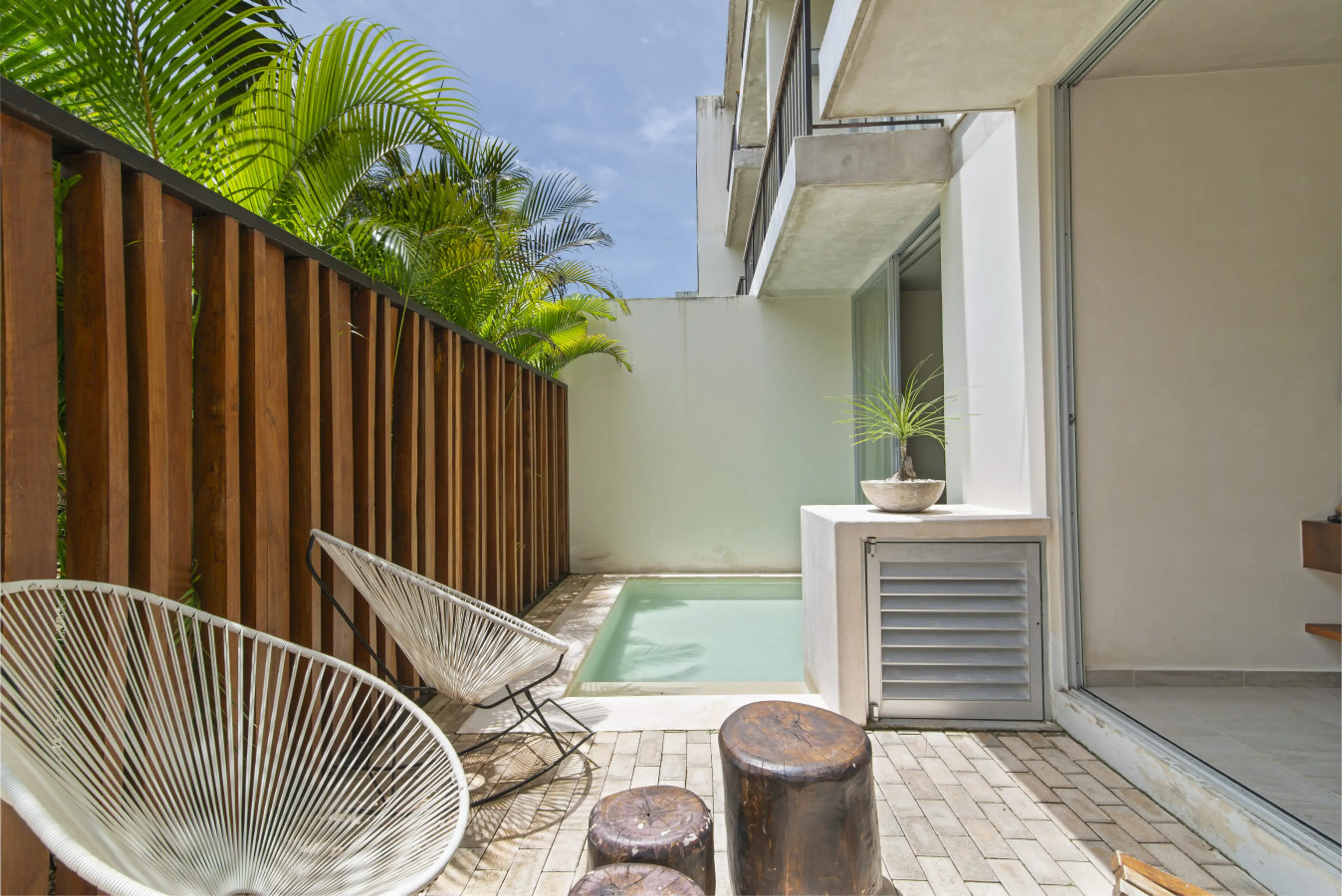 Enjoy your own private outdoor oasis with comfy chairs, wooden accents, and lush privacy—ideal for relaxing after a beach adventure.