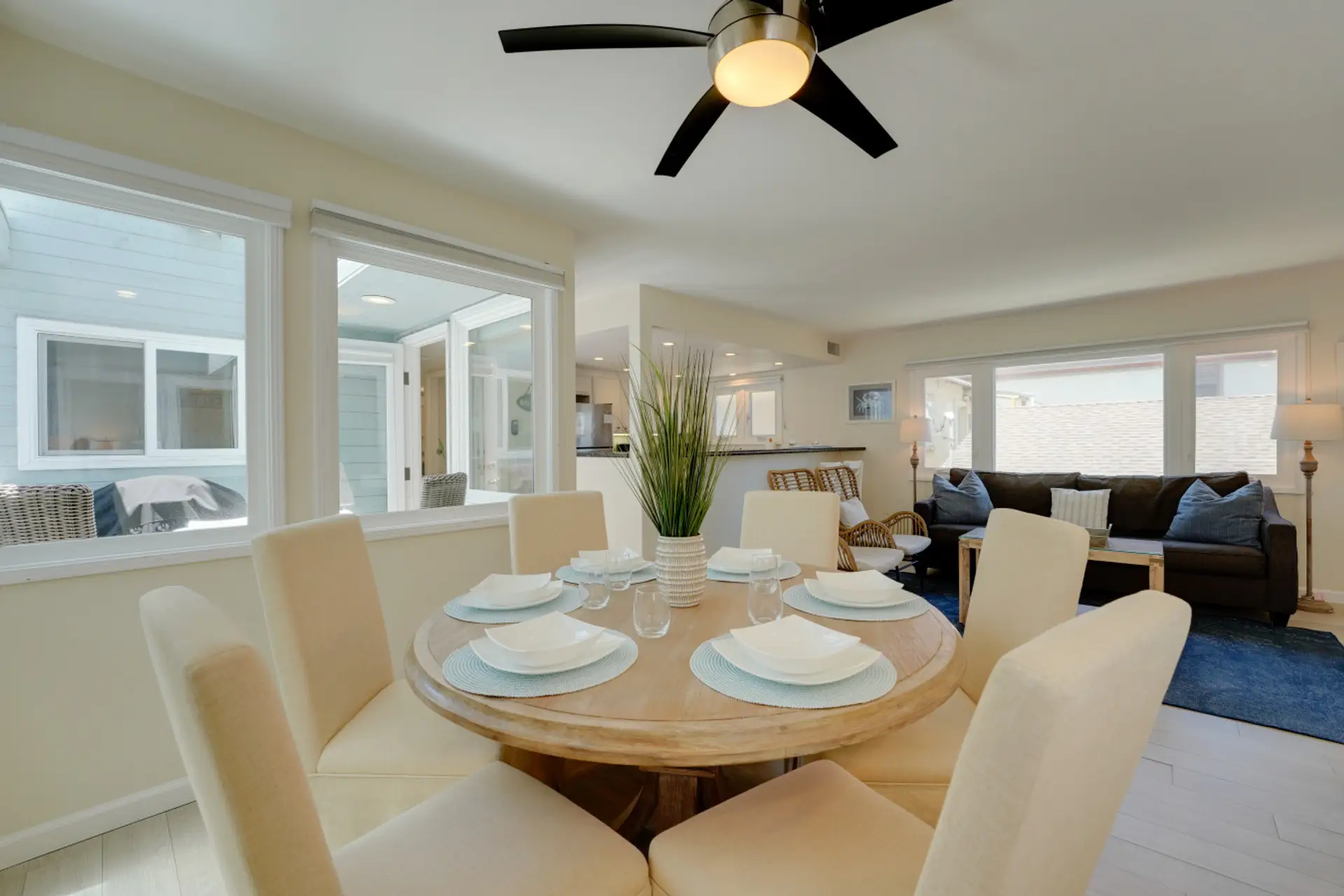 Bright and airy open-concept layout featuring a spacious living room, stylish wicker seating, bar seating at the granite breakfast counter, and a dining area with seating for six.