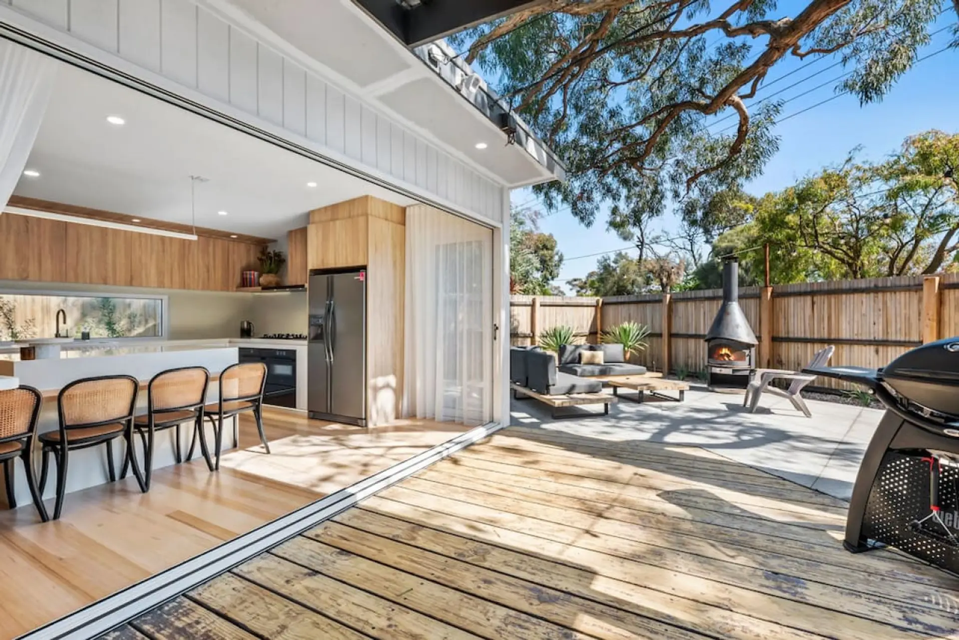 Enjoy effortless alfresco living with this spacious deck featuring a lounge area, wood-burning fireplace, and direct access to the sleek indoor kitchen