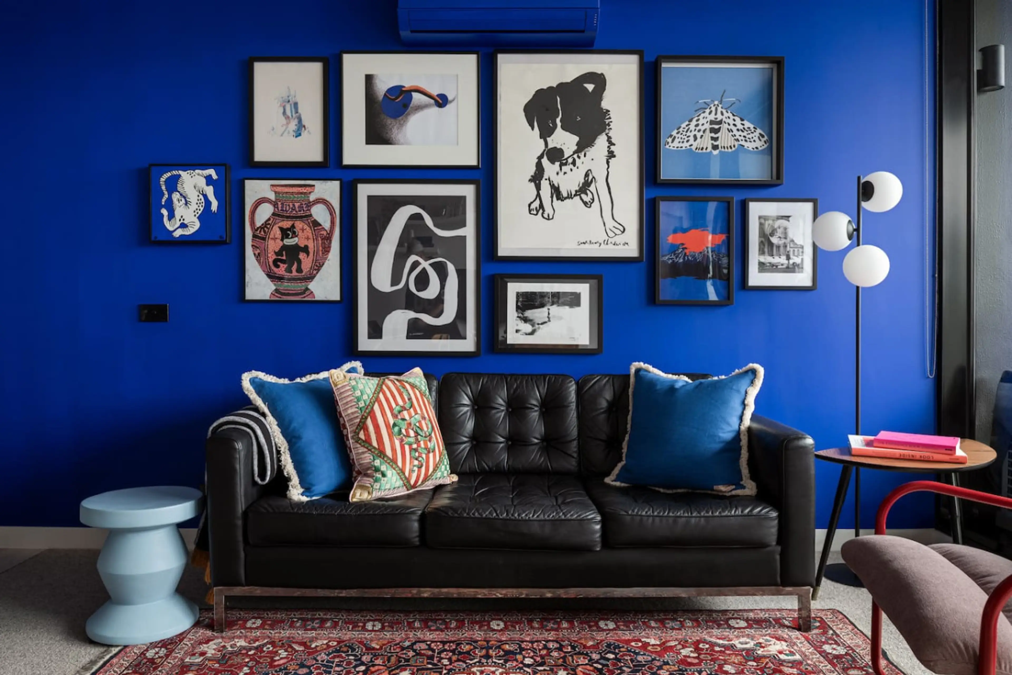 Lounge in style in this vibrant living room, featuring a bold blue wall, eclectic artwork, and a sleek leather sofa that adds a modern touch to the space