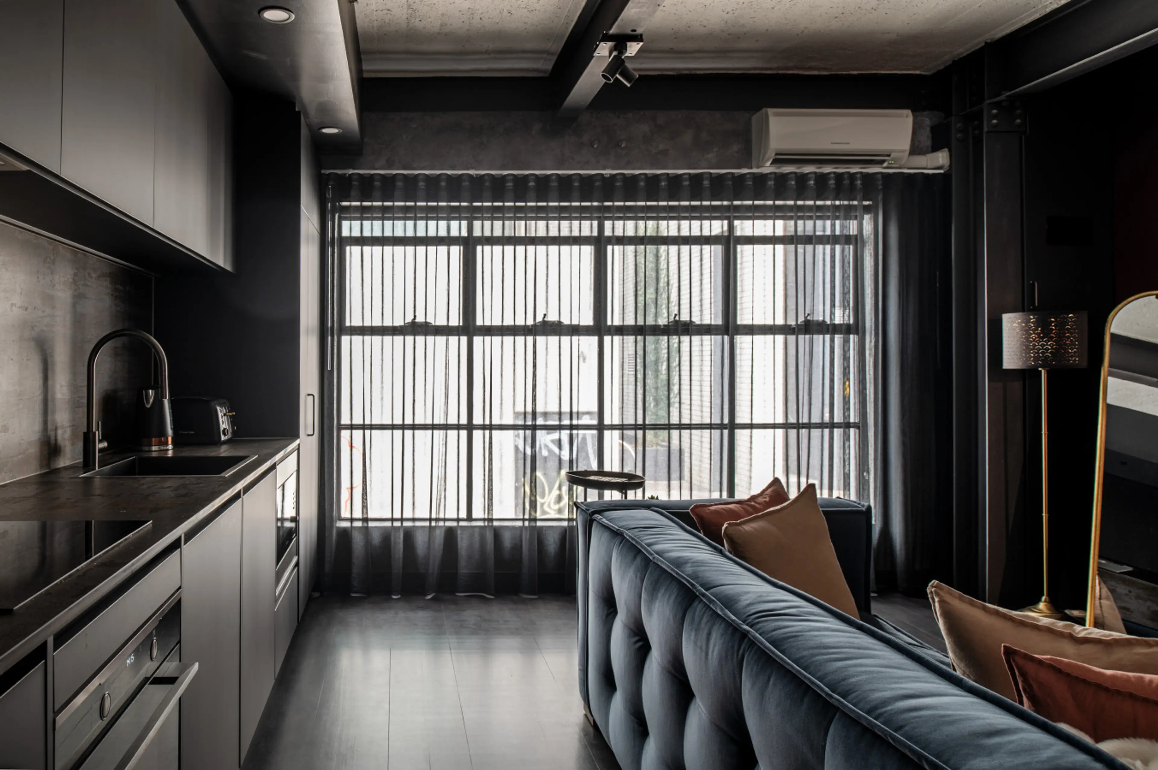 Sleek open-plan living with a modern kitchenette, plush seating and floor-to-ceiling windows that fill the space with natural light