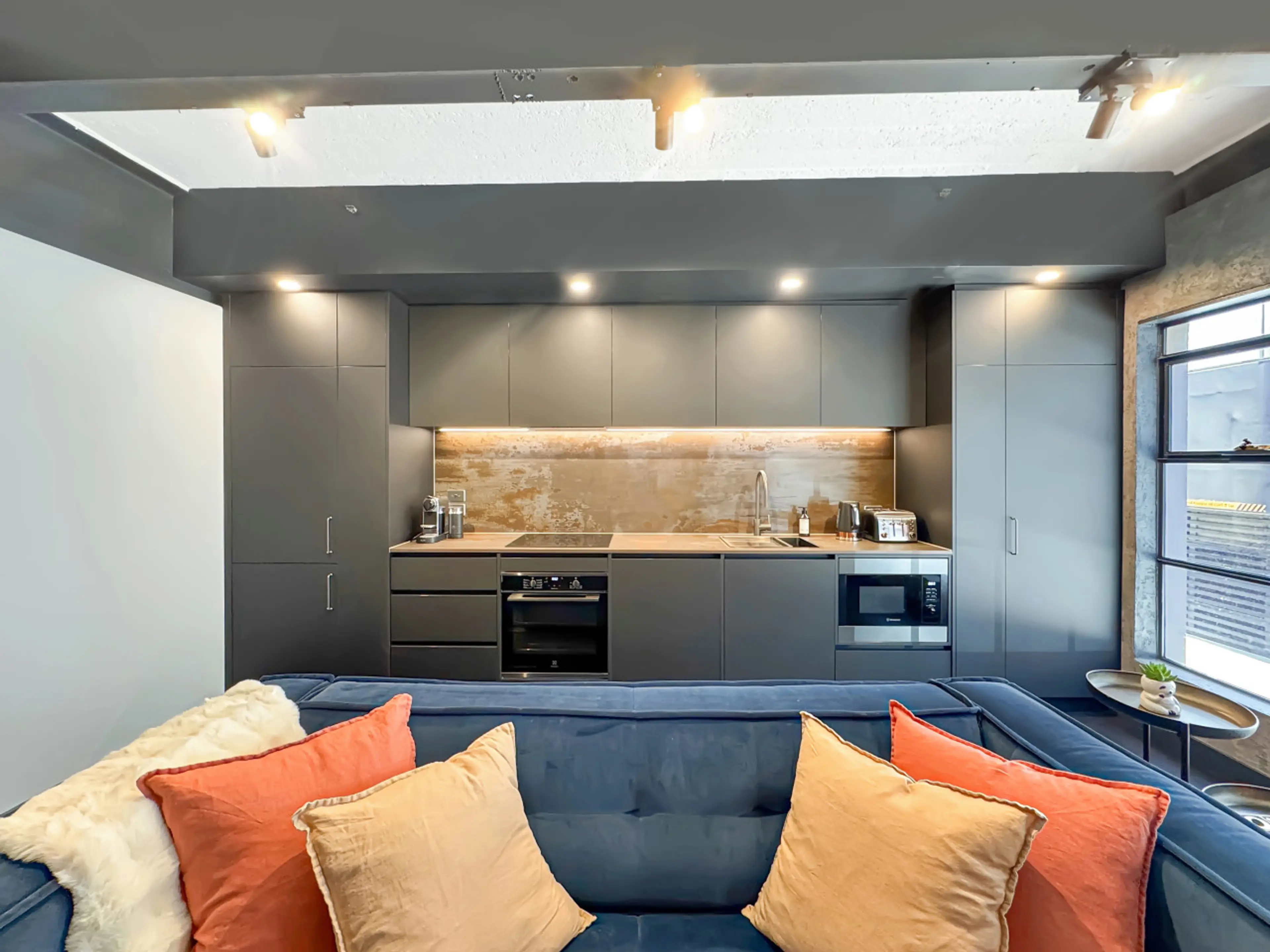 This open living zone blends bold warehouse elements with soft furnishings and warm pops of colour, creating a space that feels both edgy and inviting. The layout is perfect for unwinding after a day exploring Melbourne.