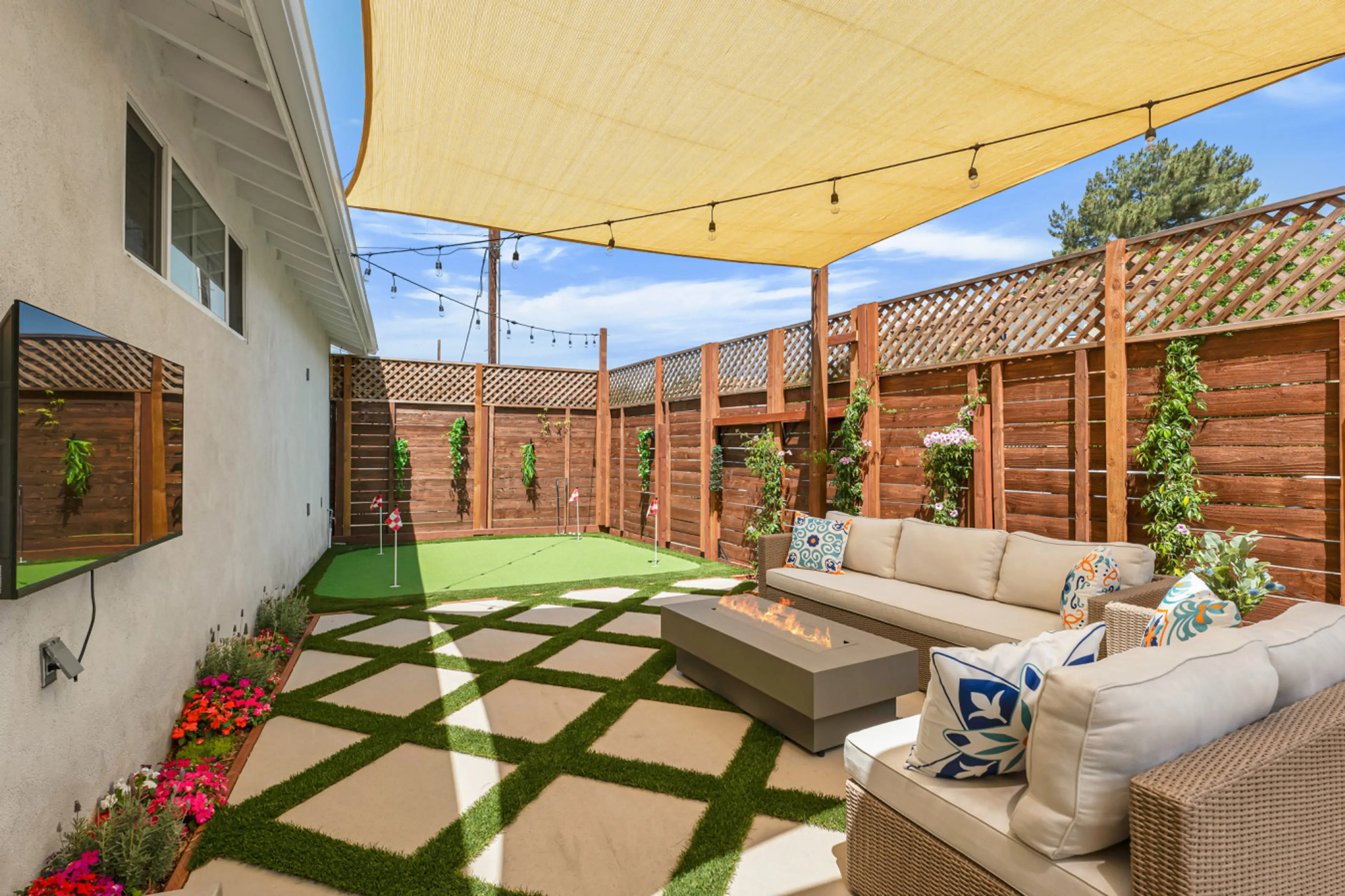 Entertainers backyard with putting green, fire pit, corn hole, bbq and dining table