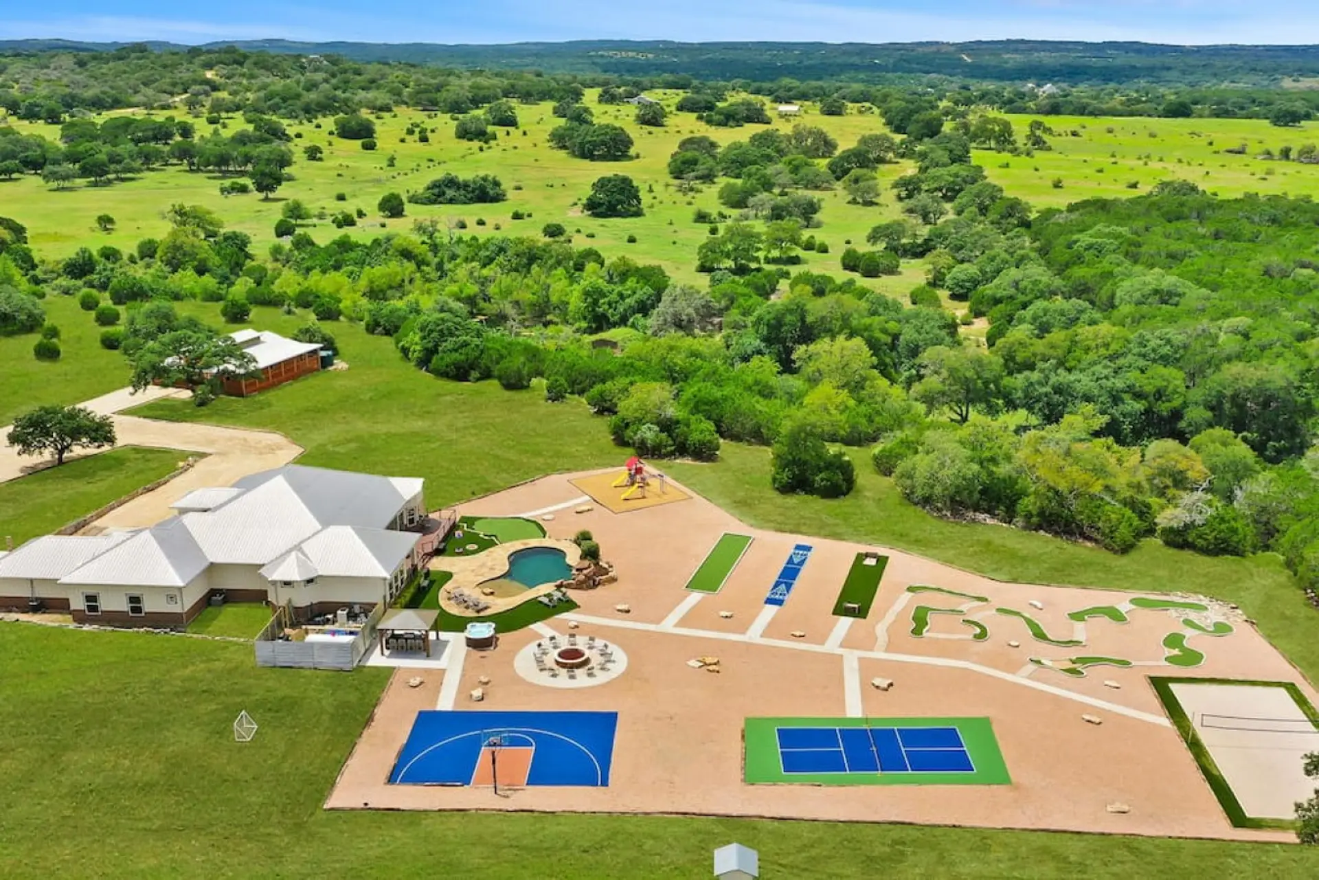 [Resort Property] Aerial view of the property showing basketball court, volleyball, pickleball, mini golf, heated pool, fire pit, and more!