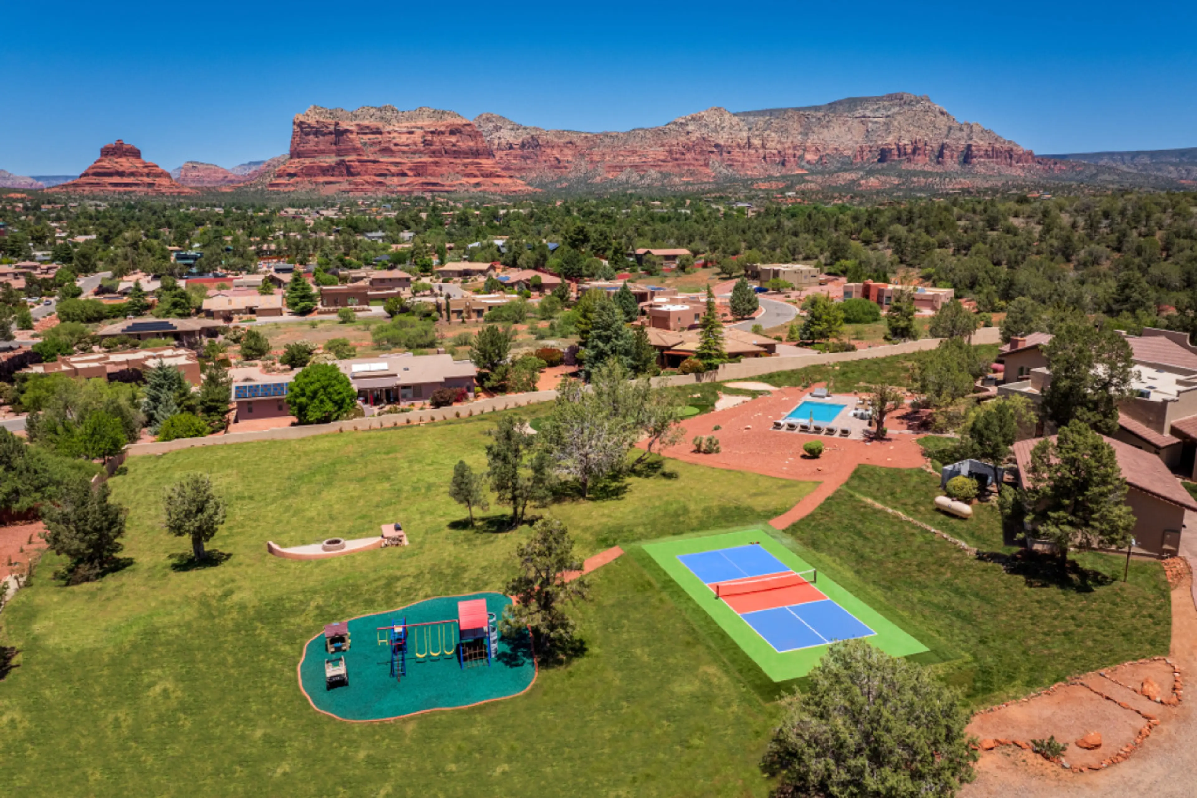 [Resort Property] Backyard heated pool and spa with fire pit, playground, and pickleball court.