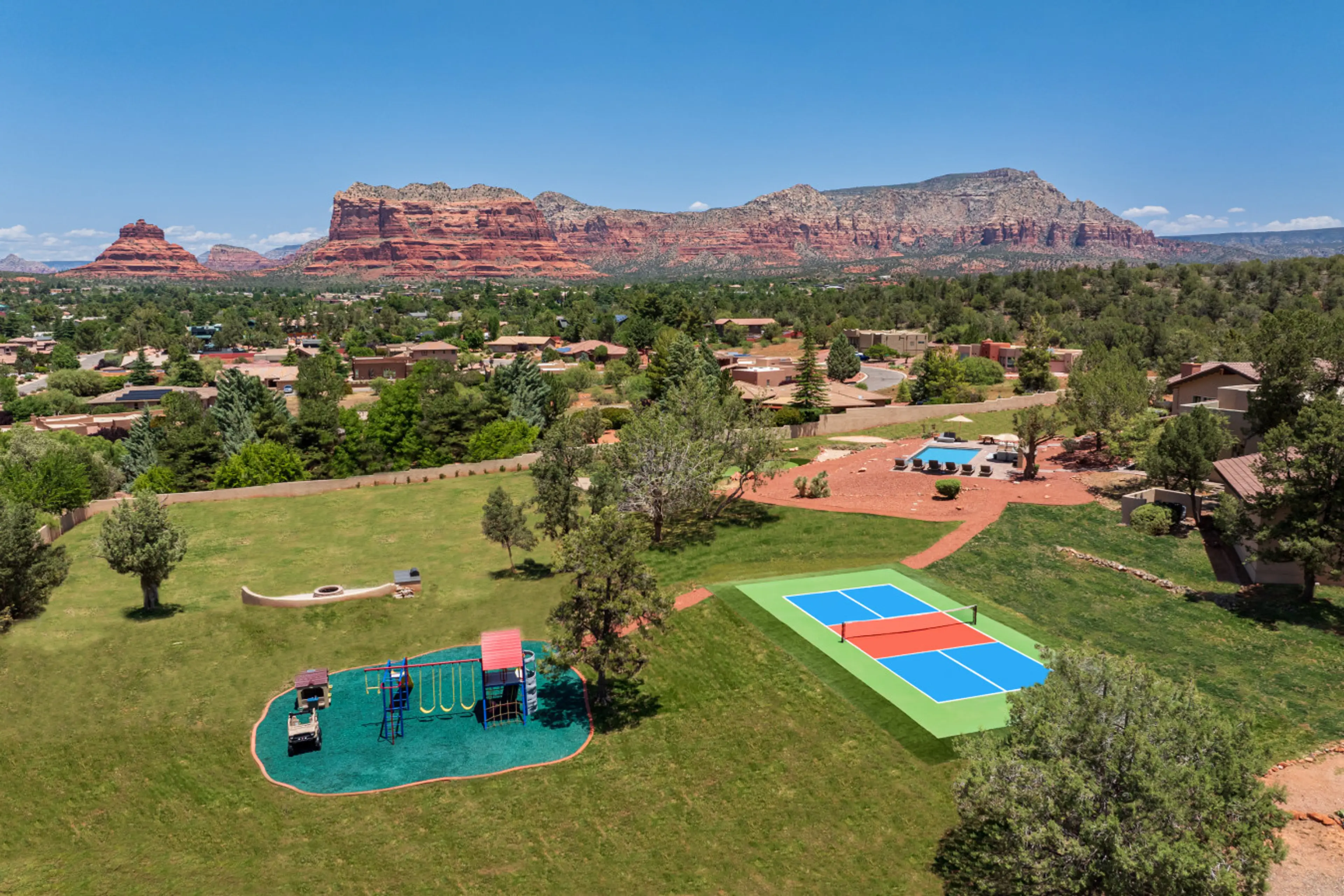 [Resort Property] Backyard heated pool and spa with fire pit, playground, and pickleball court.