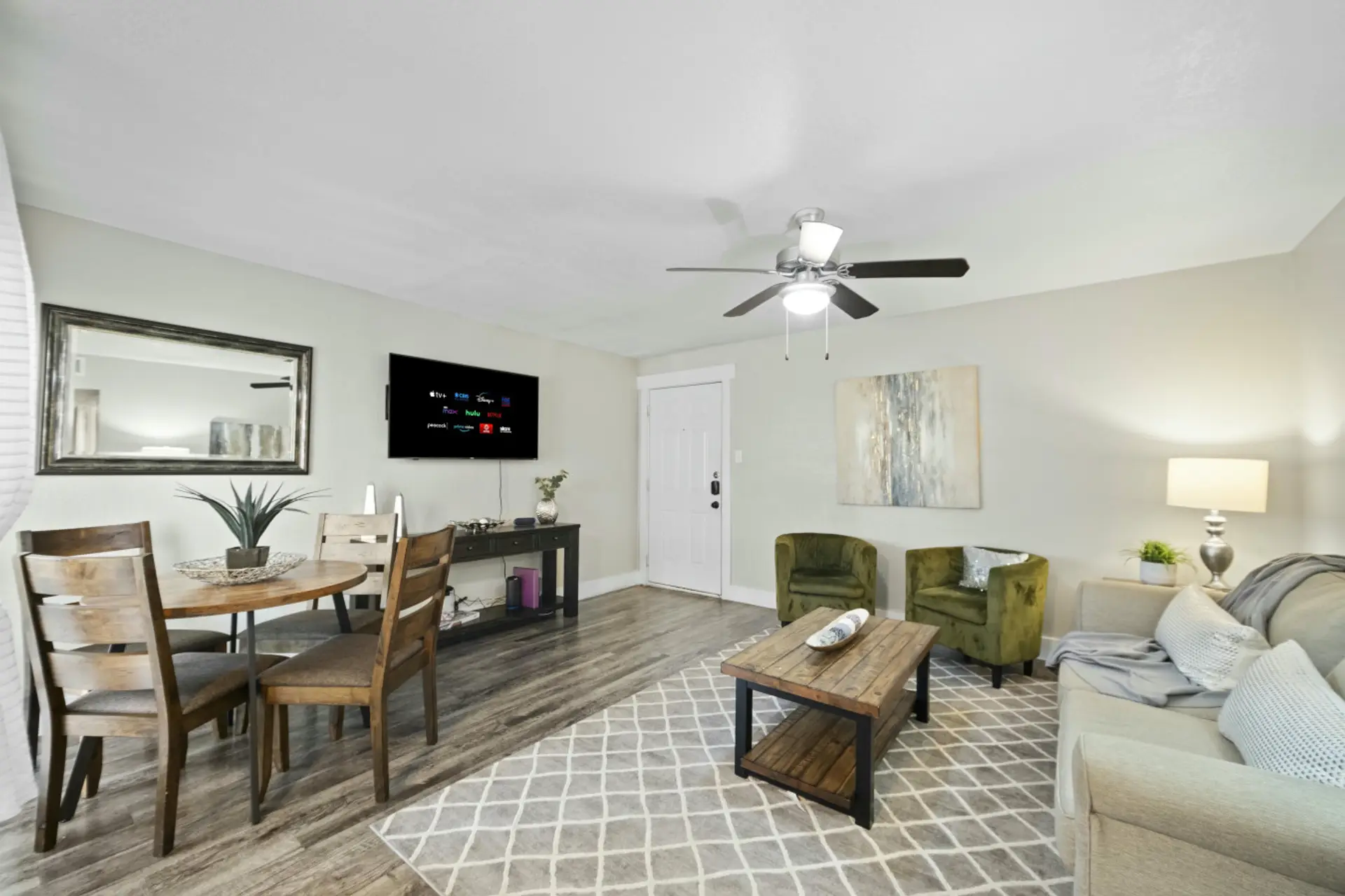 Arlington living and dining area featuring a wooden coffee table, wall-mounted TV, round dining set, and comfortable sofa seating.