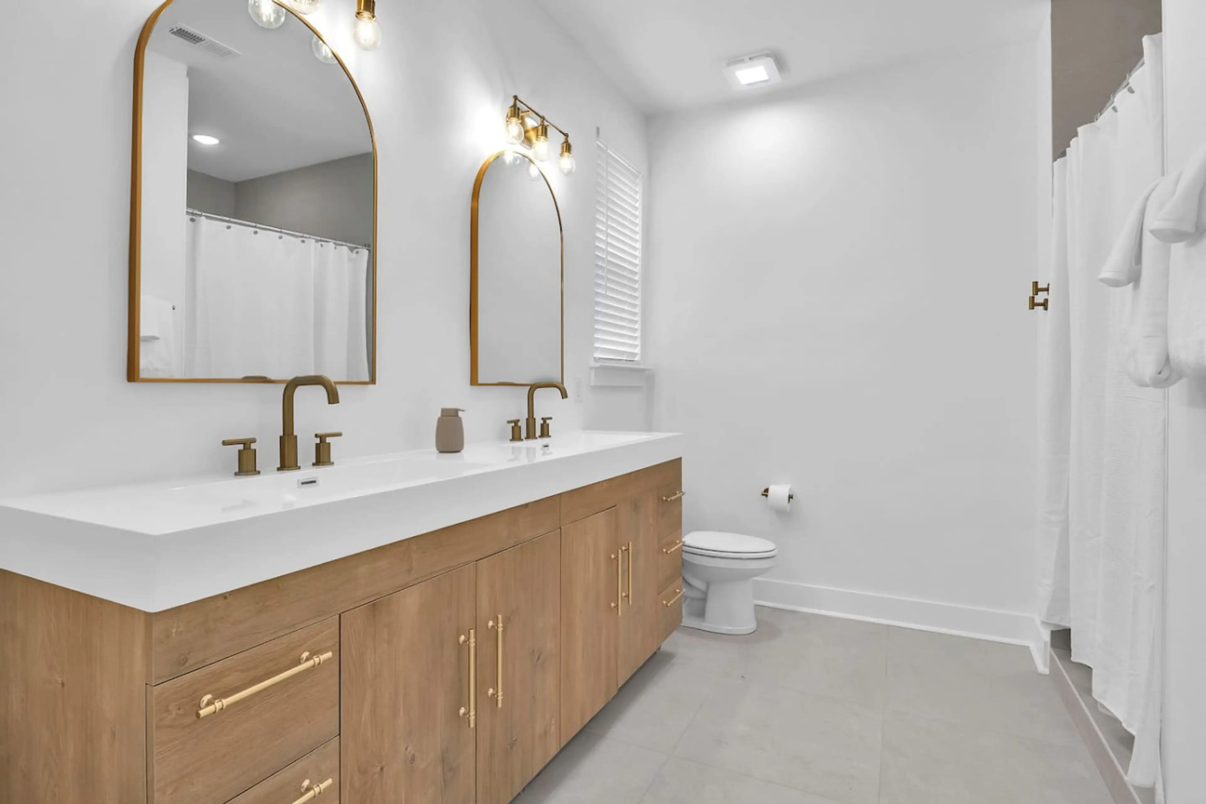 Sleek double vanity with modern gold fixtures and bright, airy finishes.
