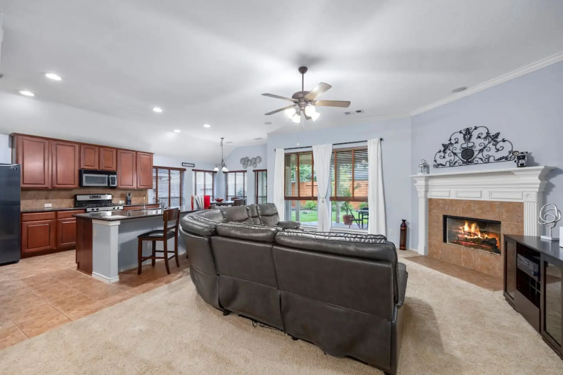 Open-concept living room with fireplace, oversized sectional, and direct flow into the kitchen and dining area — ideal for gathering together.