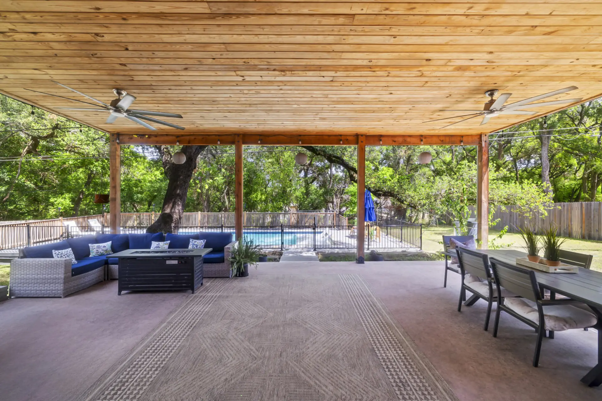 Covered outdoor patio with sectional seating, dining table, and TV — ideal for relaxing, meals, and evening hangouts