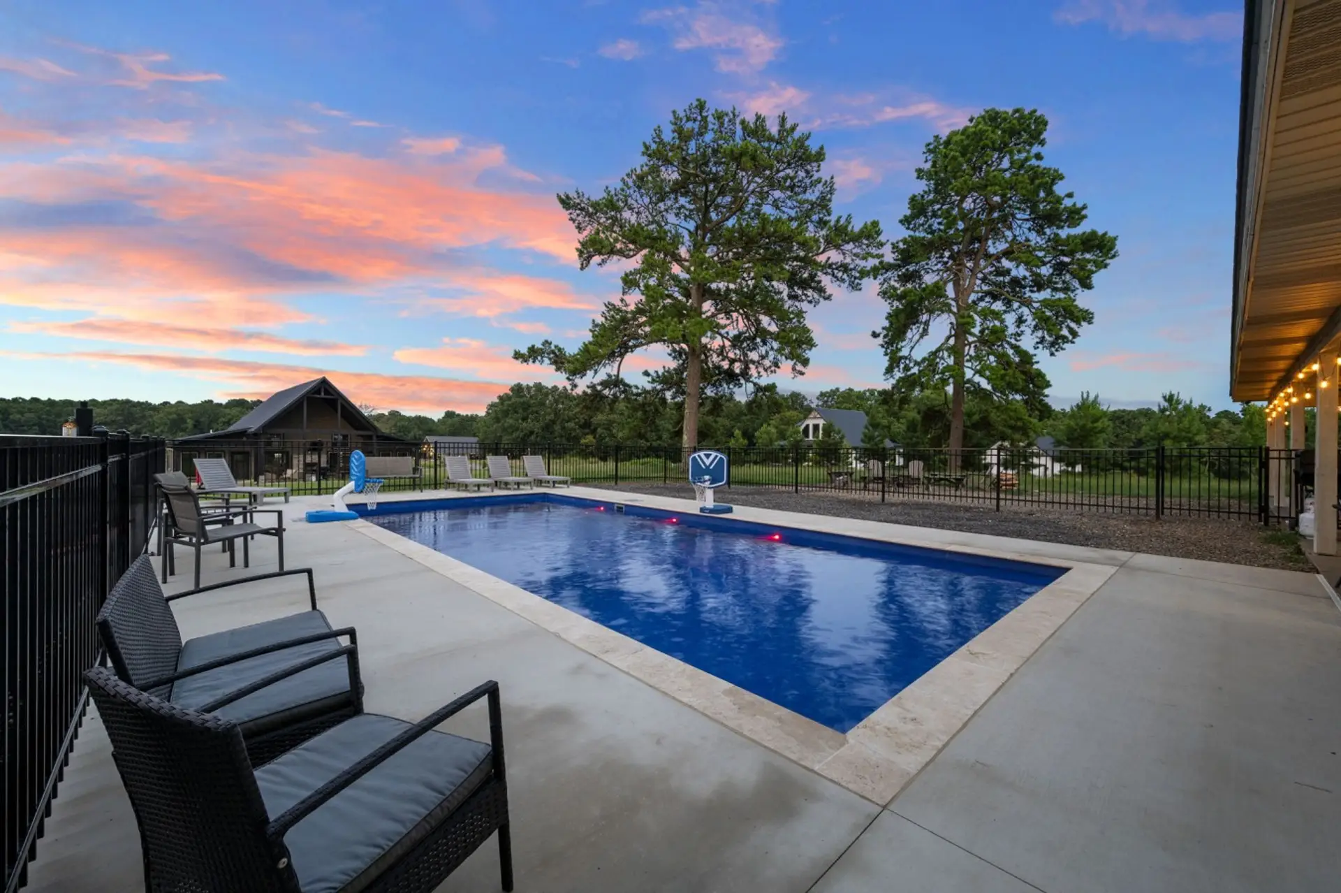 Private pool glowing at sunset with lounge seating and open sky.