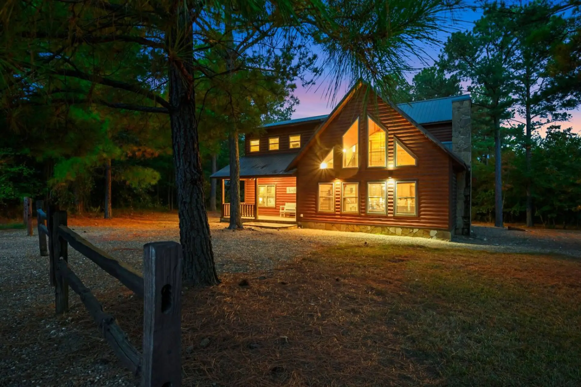 This cozy log cabin glows like a warm welcome in the piney woods, perfect for a peaceful getaway surrounded by those gorgeous old trees.